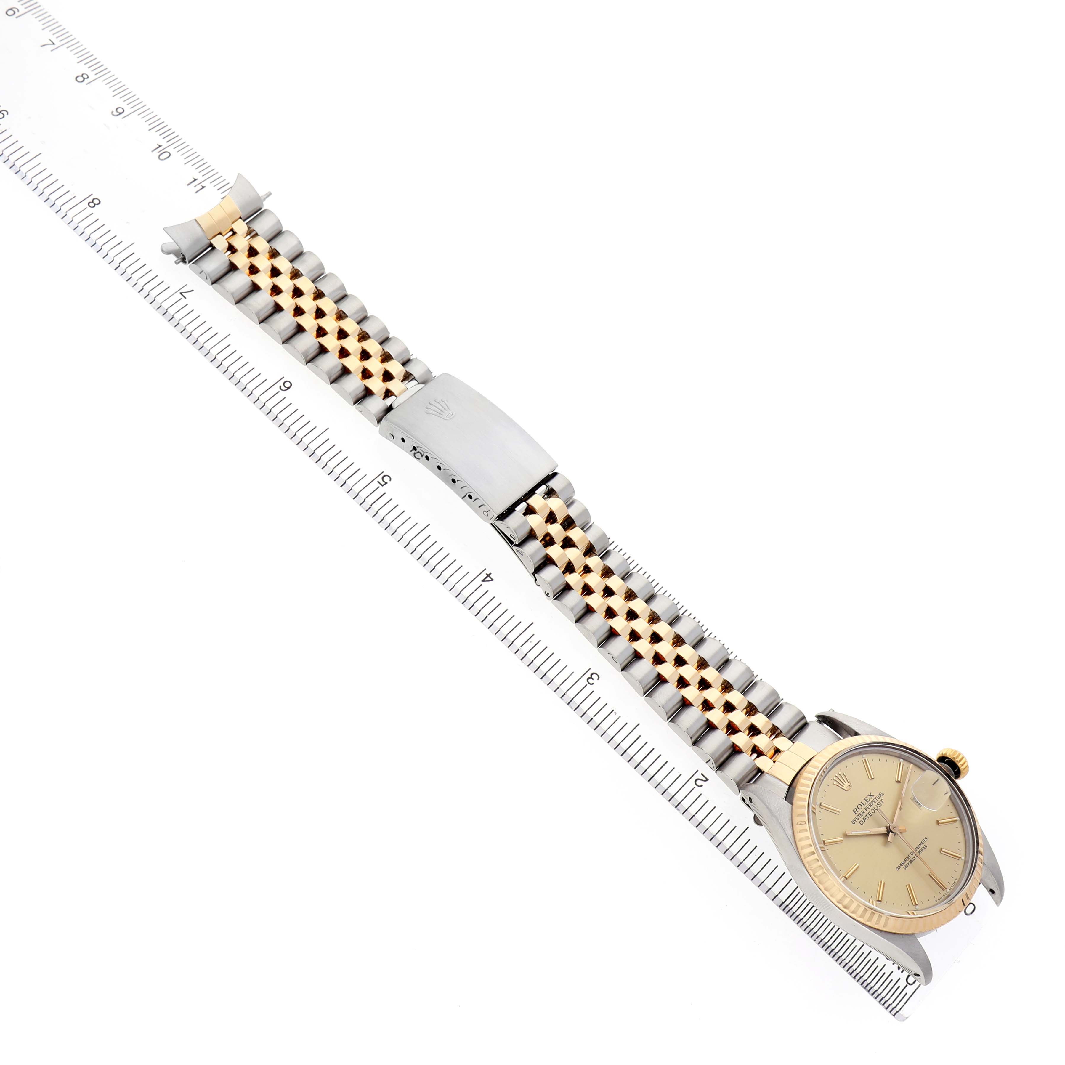 The image shows a Rolex Datejust 16013 Men's Steel and Gold (two tone) Champagne Dial watch at a slight angle, highlighting the gold and silver bracelet, clasp, and face with a ruler for scale.