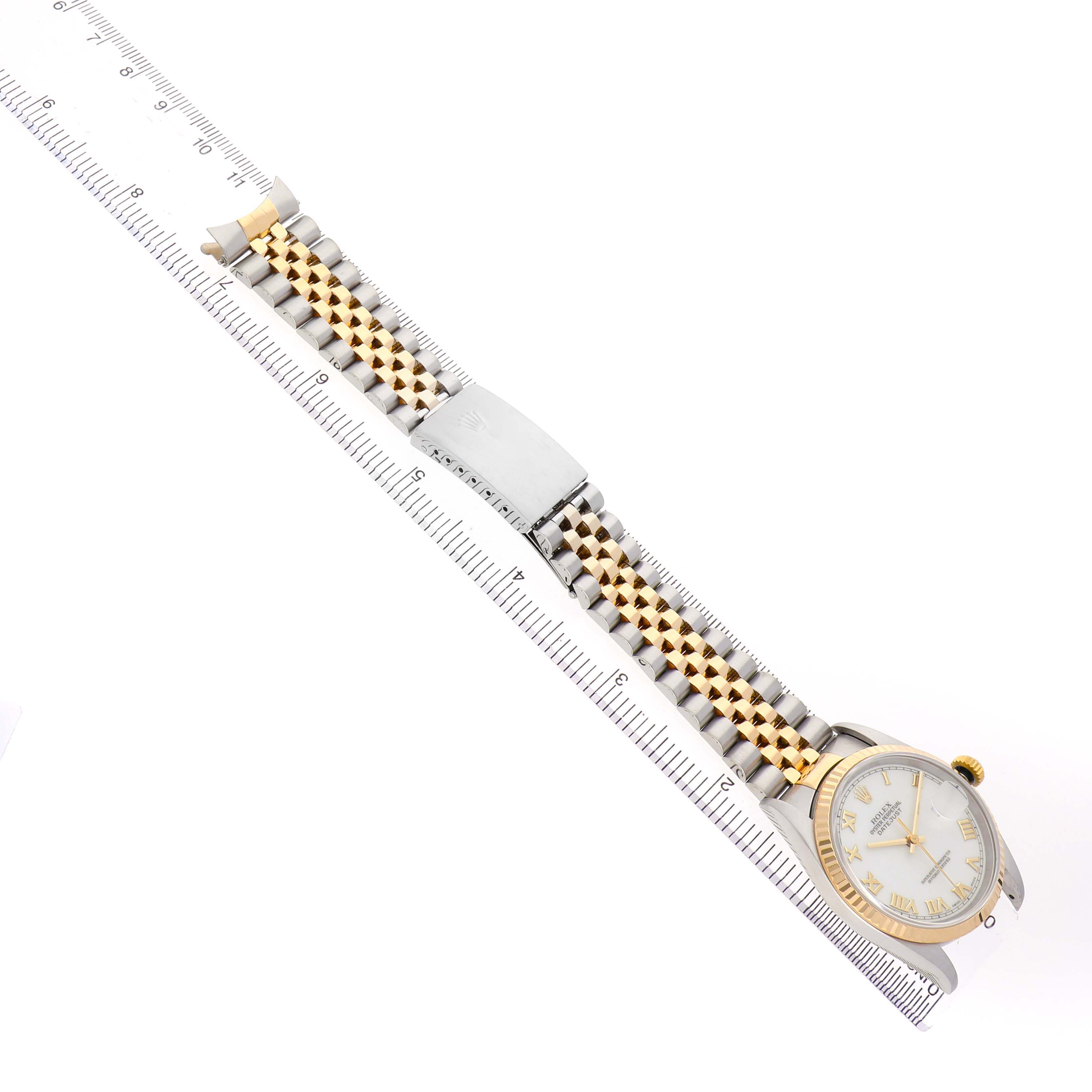 The Rolex Datejust 16233 Men's Steel and Gold (two tone) White Dial watch is displayed from a top angle, showing the face, bracelet, and clasp alongside a ruler for scale.