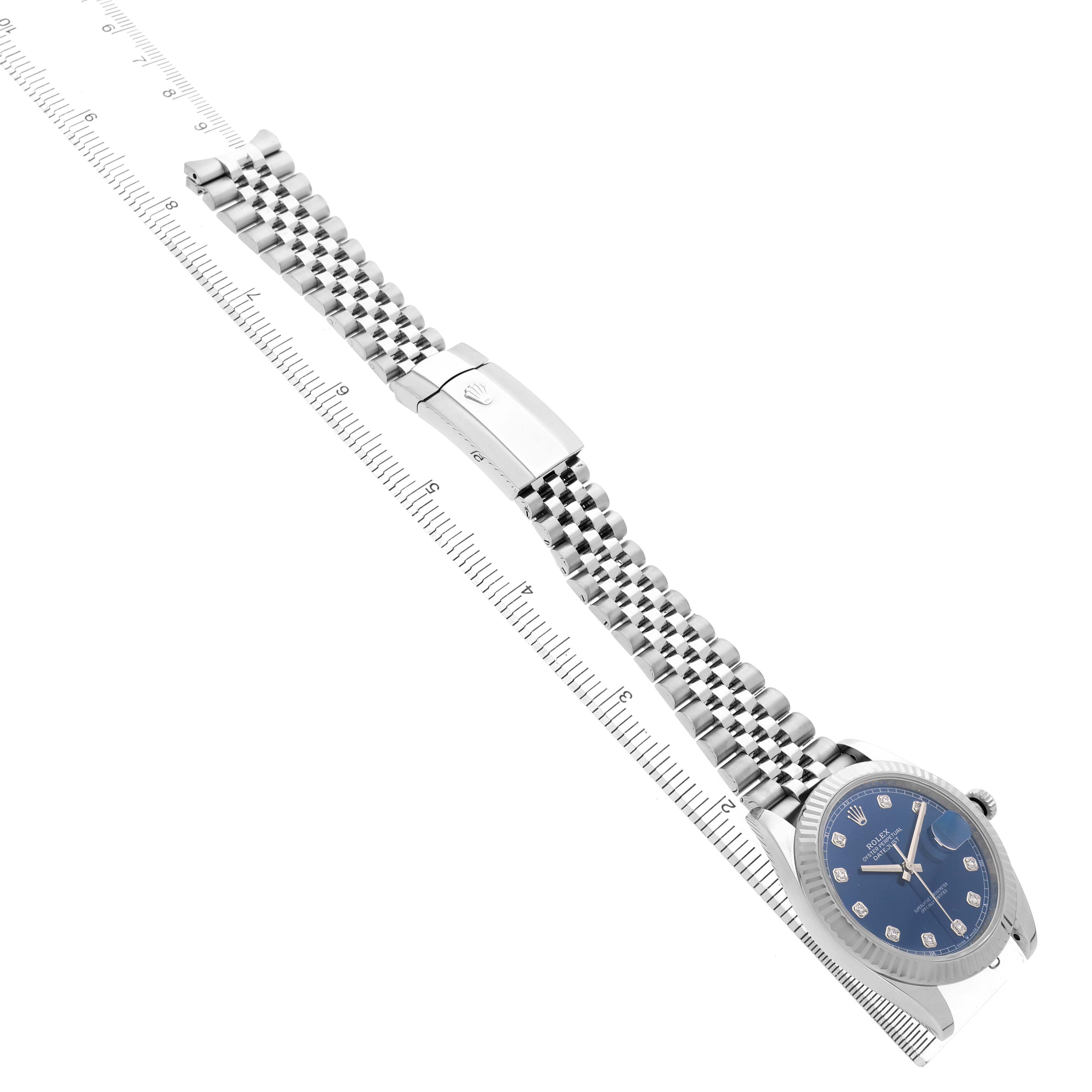 The image shows a Rolex Datejust 41 126334 Men's Stainless Steel Blue Dial watch at an angled view, highlighting its face, bracelet, and clasp alongside a ruler.