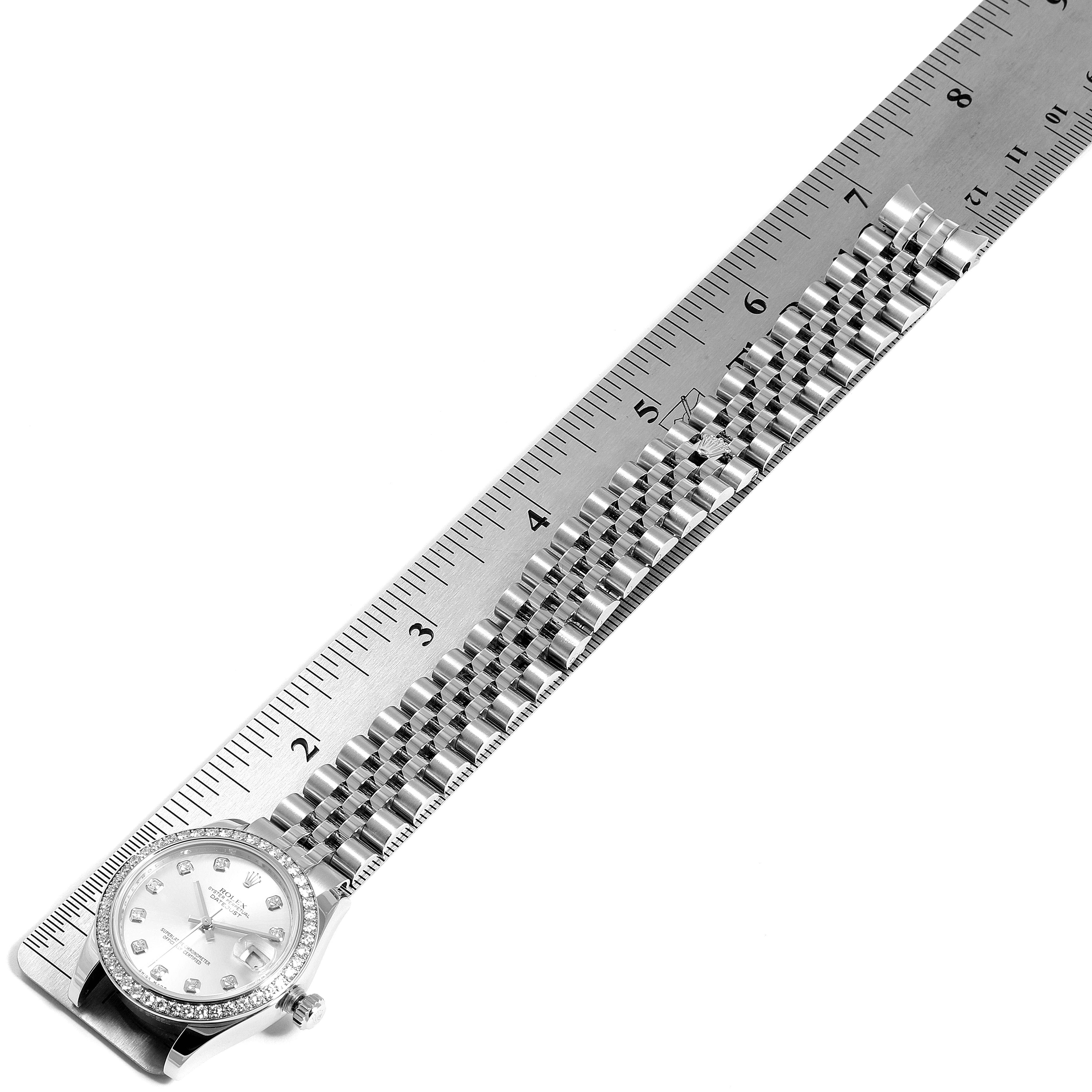 The image shows a full top-down view of a Rolex Mid-Size 178384 Women
s Stainless Steel Silver Dial 178384 Women
s Stainless Steel Silver Dial watch, including its face, bracelet, and a ruler for scale.