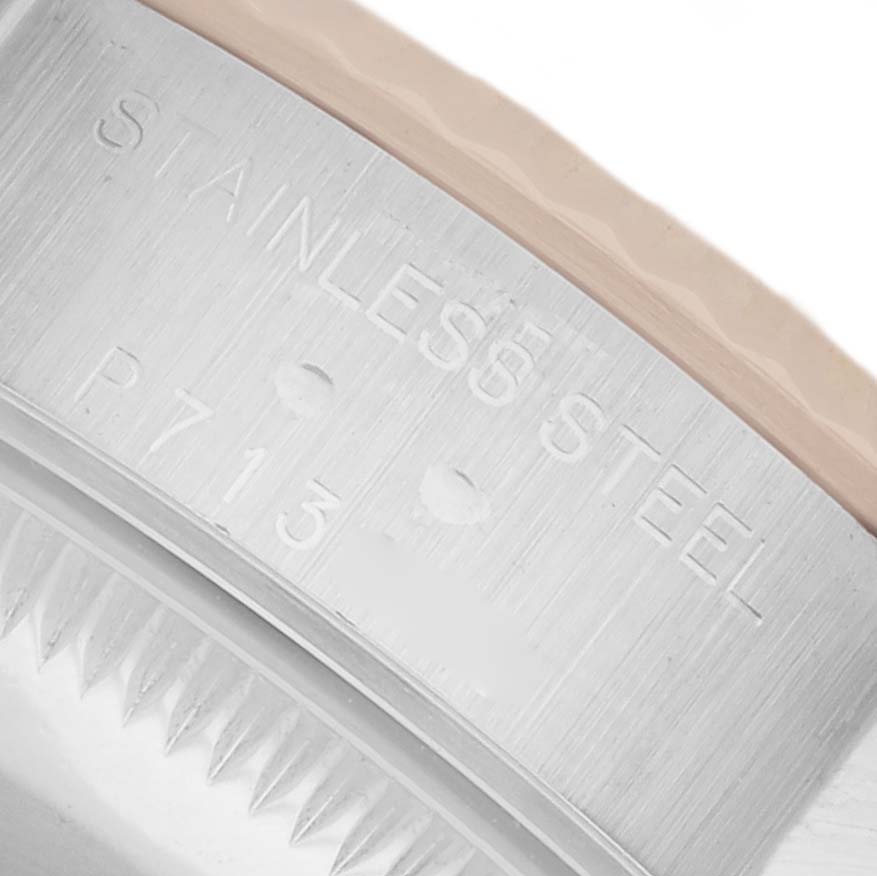 The image shows a close-up of the stainless steel case edge of a Rolex Datejust 79173 Women
s Steel and Gold (two tone) Champagne Dial watch, displaying engravings and the bezel
s teeth.