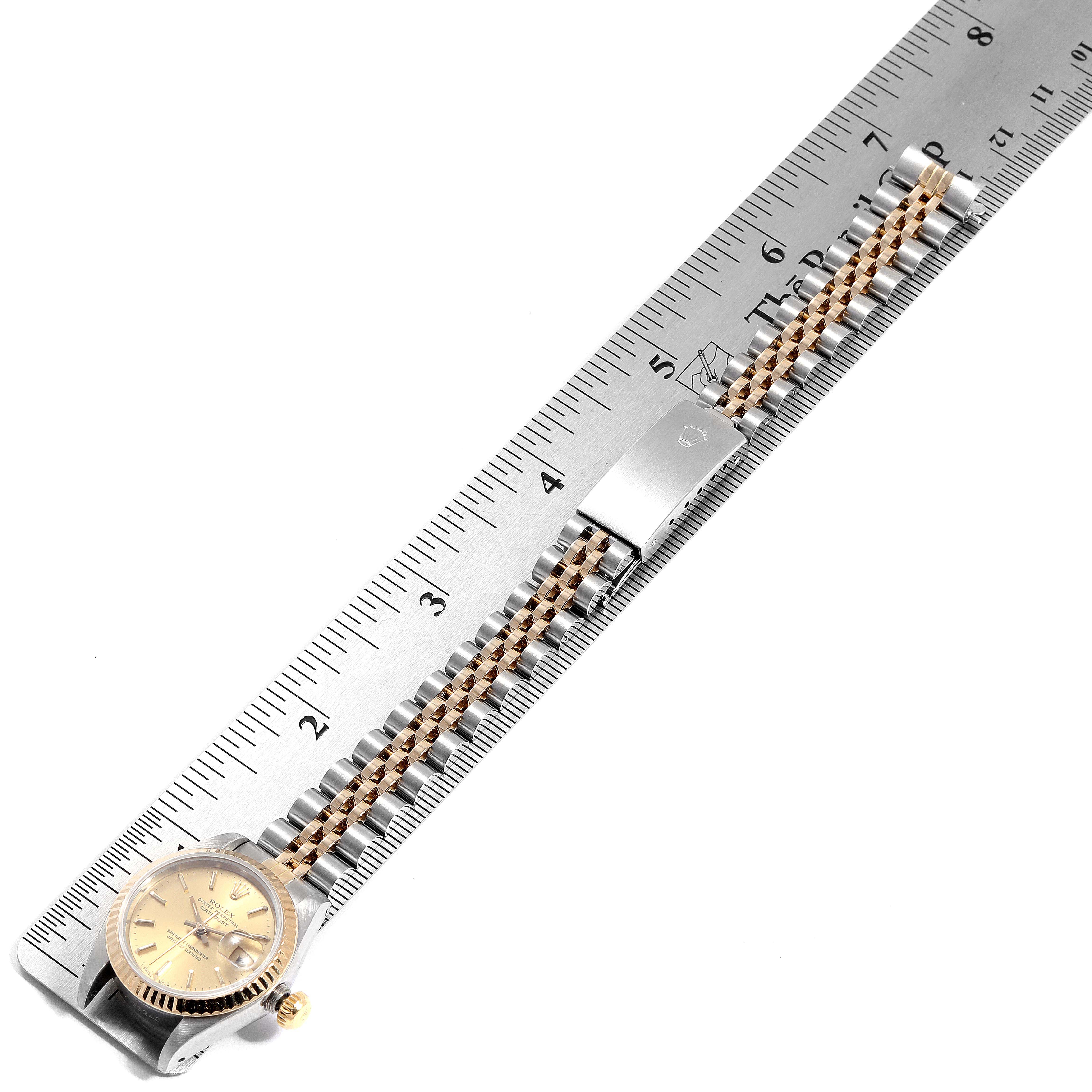 The image shows a Rolex Datejust 69173 Women's Steel and Gold (two tone) Champagne Dial 69173 Women's Steel and Gold (two tone) Champagne Dial watch laid flat against a ruler, highlighting the face, clasp, and bracelet.