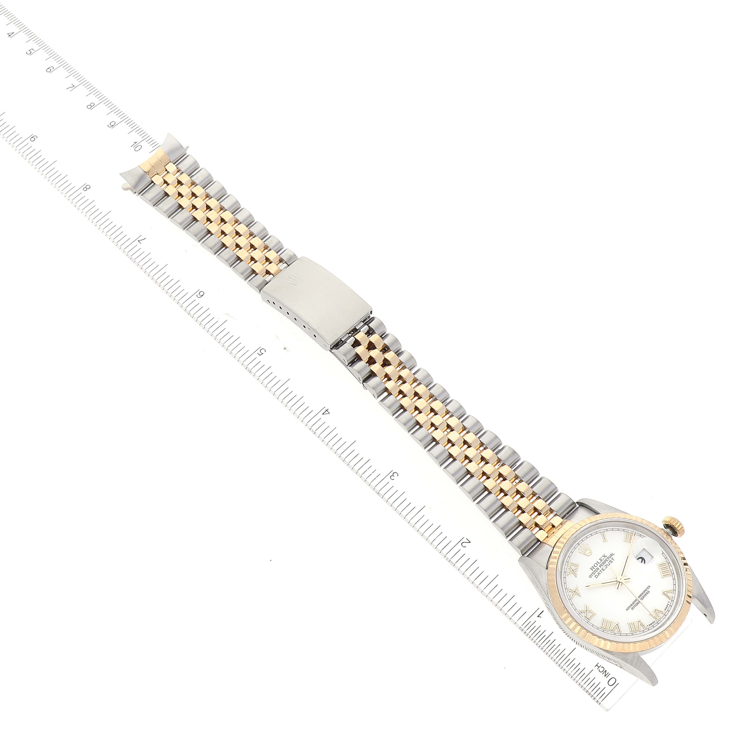 The image shows a top-down view of a Rolex Datejust 16233 Men's Steel and Gold (two tone) White Dial 16233 Men's Steel and Gold (two tone) White Dial watch laid flat next to a ruler, showcasing its band and face.