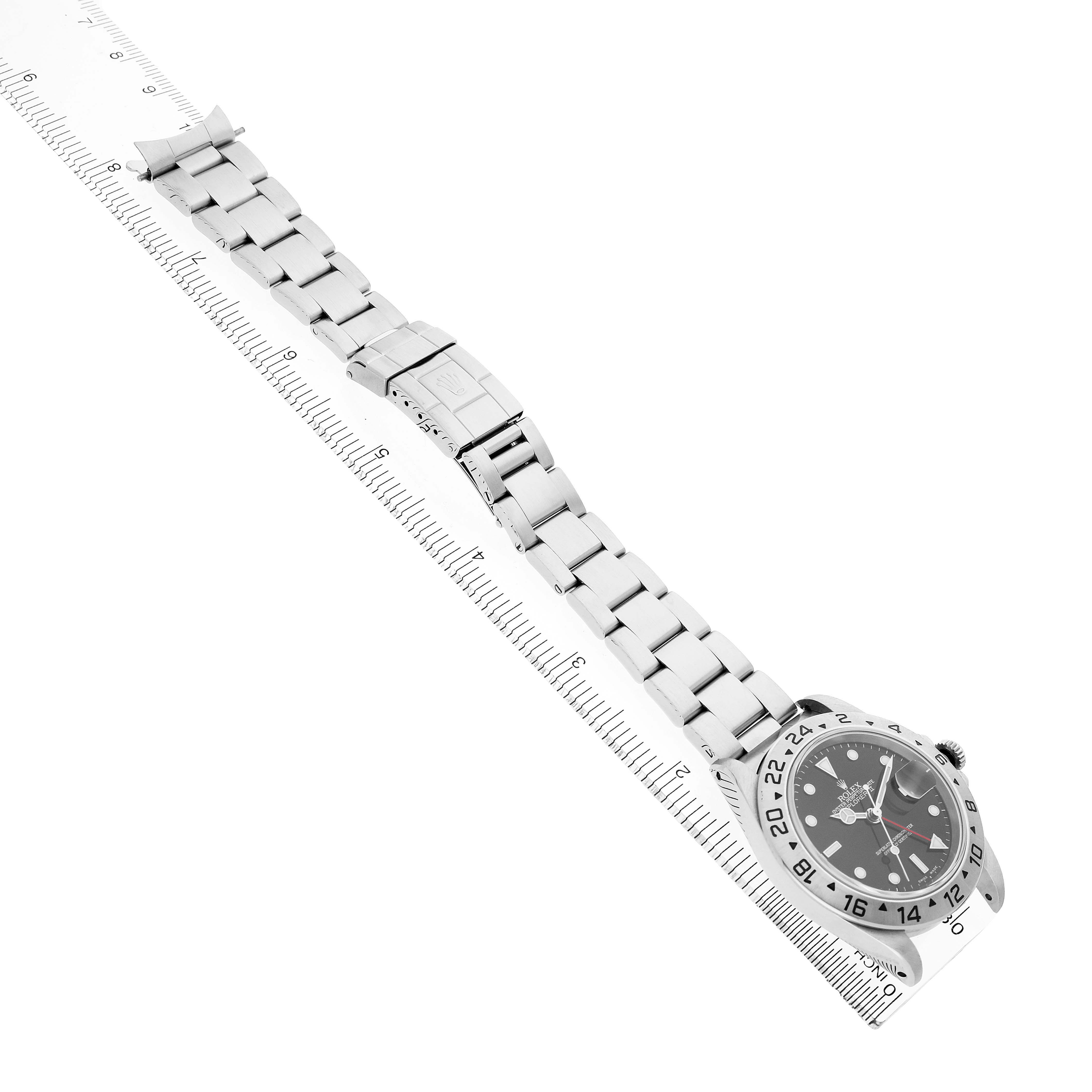 The Rolex Explorer 16570 Men's Stainless Steel Black Dial watch is shown at a diagonal angle, displaying the bracelet, clasp, and face with a ruler for scale.