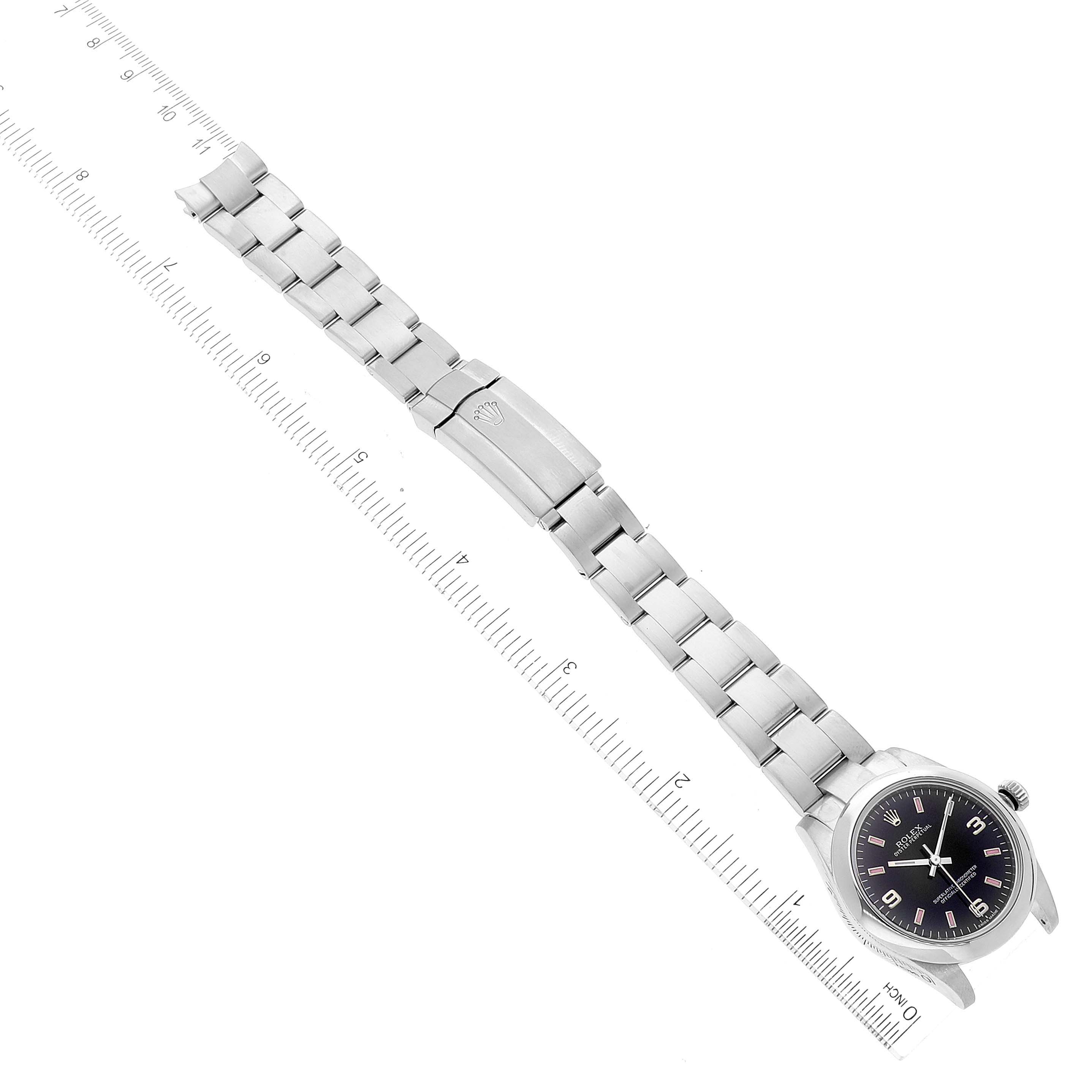 The image shows a flat-lay view of a Rolex Mid-Size 177200 Women
s Stainless Steel Black Dial 177200 Women
s Stainless Steel Black Dial watch with its bracelet extended alongside a ruler for scale.