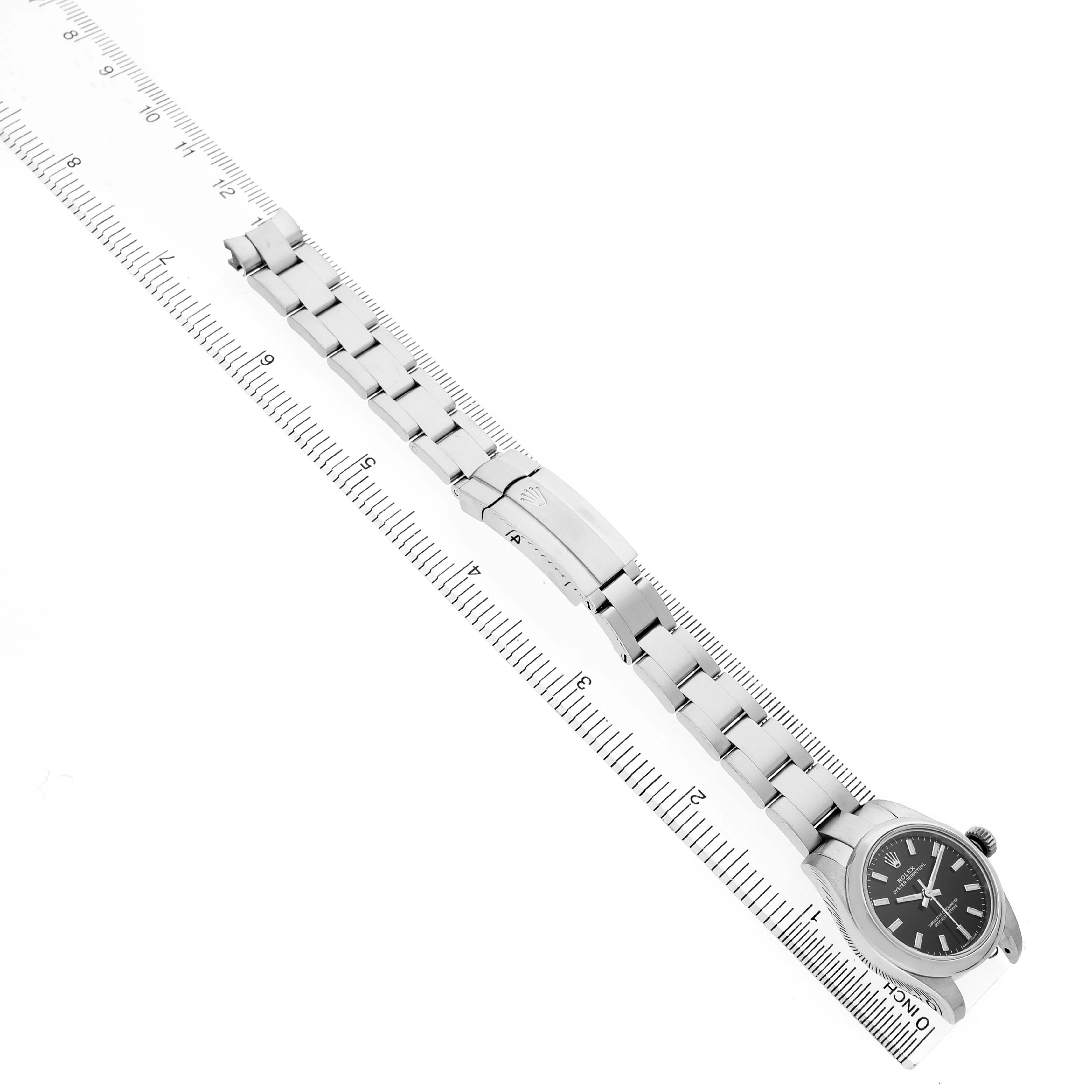 The Rolex Oyster Perpetual 176200 Women's Stainless Steel Black Dial watch is displayed at an angle, highlighting the strap, clasp, and face next to a ruler for scale.