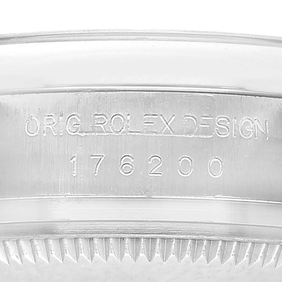 The image shows a close-up of the Rolex Oyster Perpetual 176200 Women's Stainless Steel Silver Dial case side with engraved serial and design numbers.