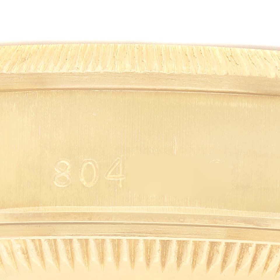 The image shows a close-up of the fluted bezel of a Rolex President 69278 Women
s Yellow Gold Champagne Dial model watch.