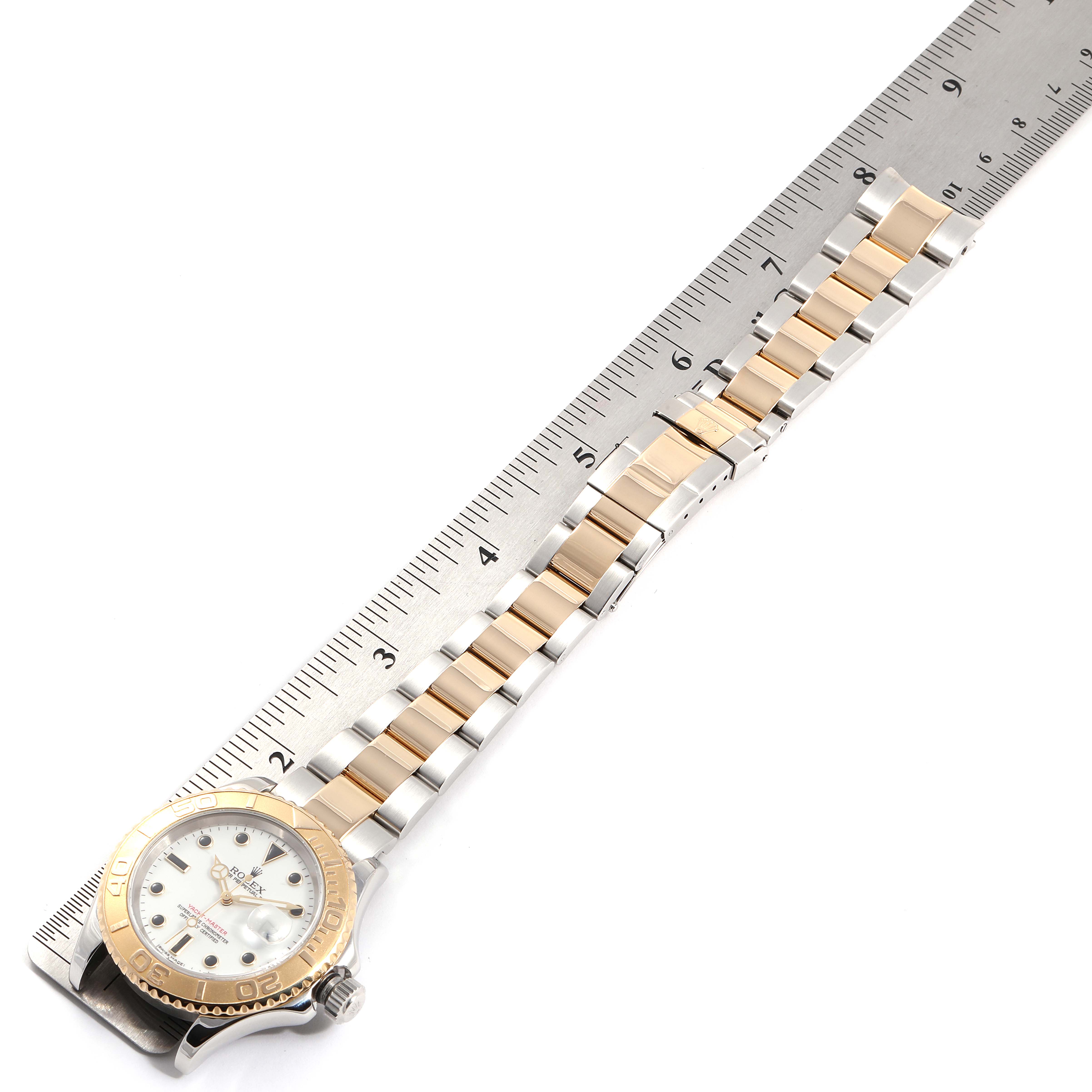 The image shows a Rolex Yacht-Master 16623 Men
s Steel and Gold (two tone) White Dial 16623 Men
s Steel and Gold (two tone) White Dial watch placed horizontally alongside a ruler, highlighting the watch band and bezel.