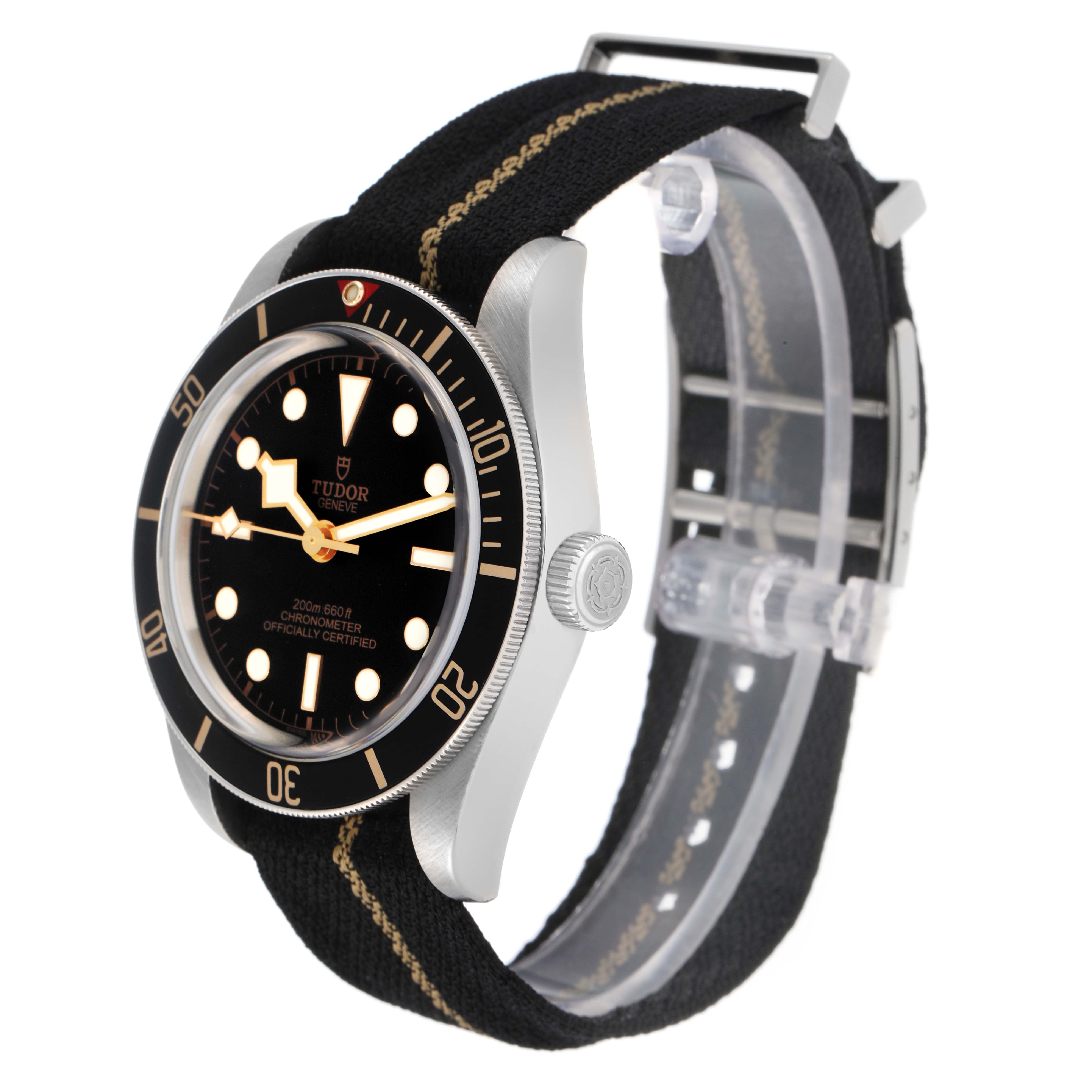 The Tudor Heritage Black Bay 79030N Men
s Stainless Steel Black Dial watch is shown at a 3/4 side angle, displaying the face, bezel, crown, and fabric strap.