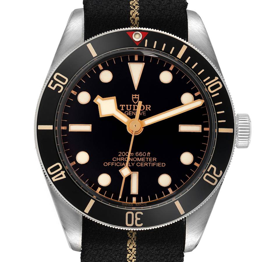 The Tudor Heritage Black Bay model 79030N watch is shown from the front, highlighting its black dial, luminous markers, and bezel, with a fabric strap.
