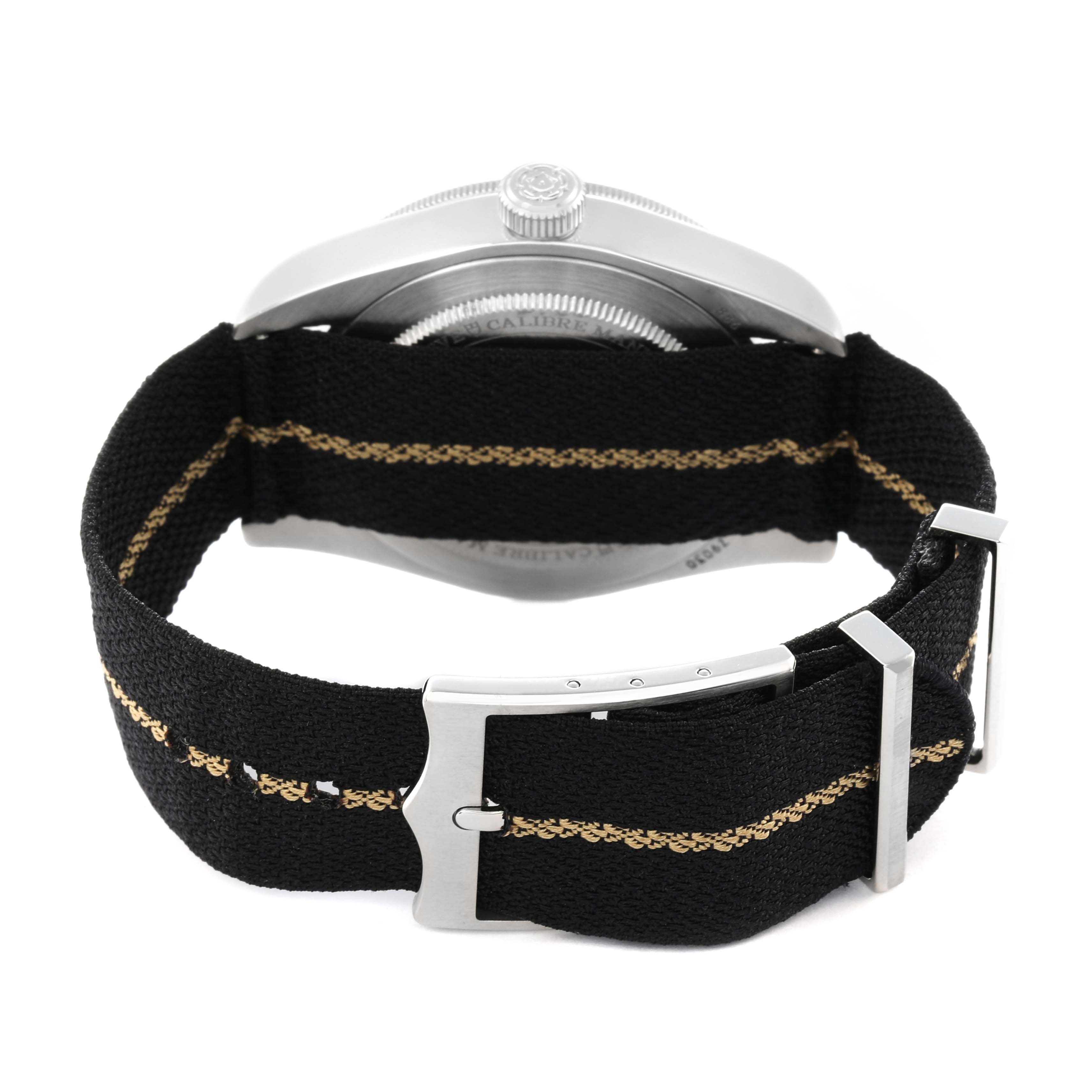 The Tudor Heritage Black Bay 79030N Men
s Stainless Steel Black Dial watch is shown from the back, highlighting the underside of the case and the fabric strap with clasp.