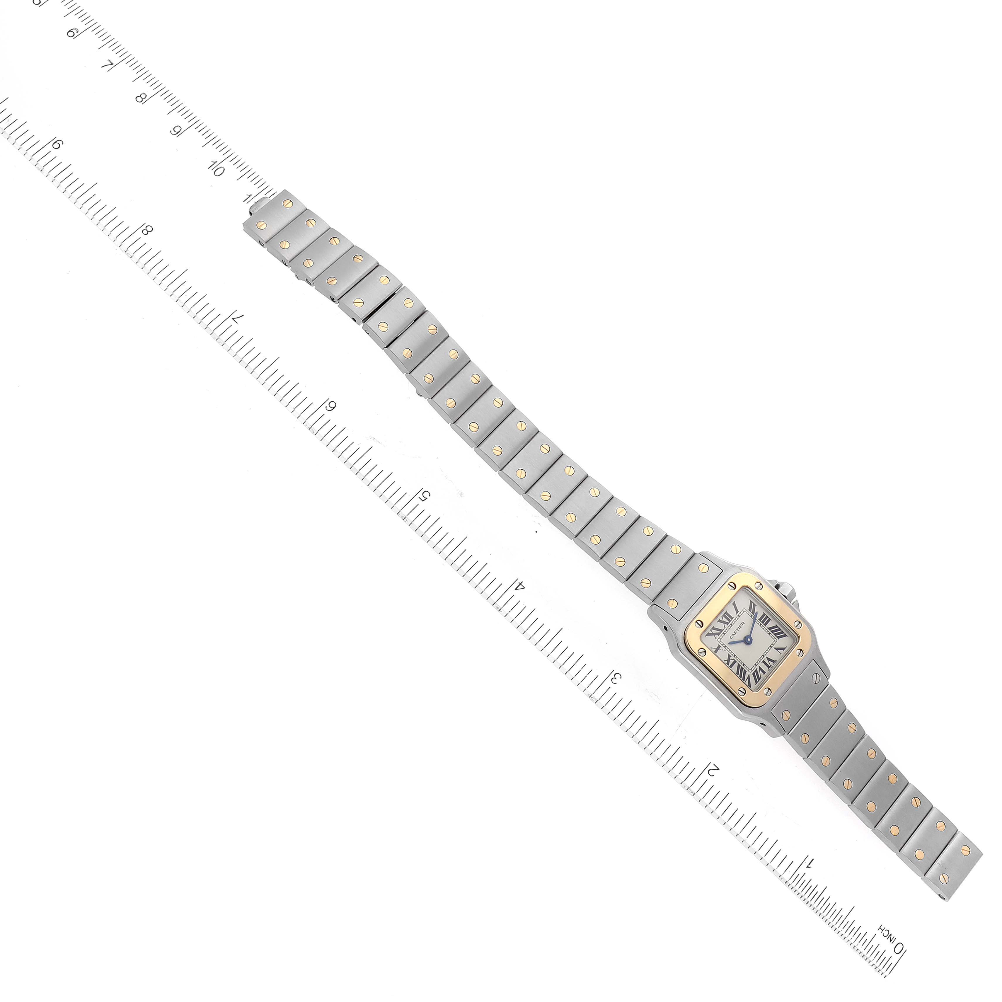 The image shows an overhead view of a Cartier Santos W20012C4 Women's Steel and Gold (two tone) White Dial W20012C4 Women's Steel and Gold (two tone) White Dial watch with its strap extended alongside a ruler for measurement.