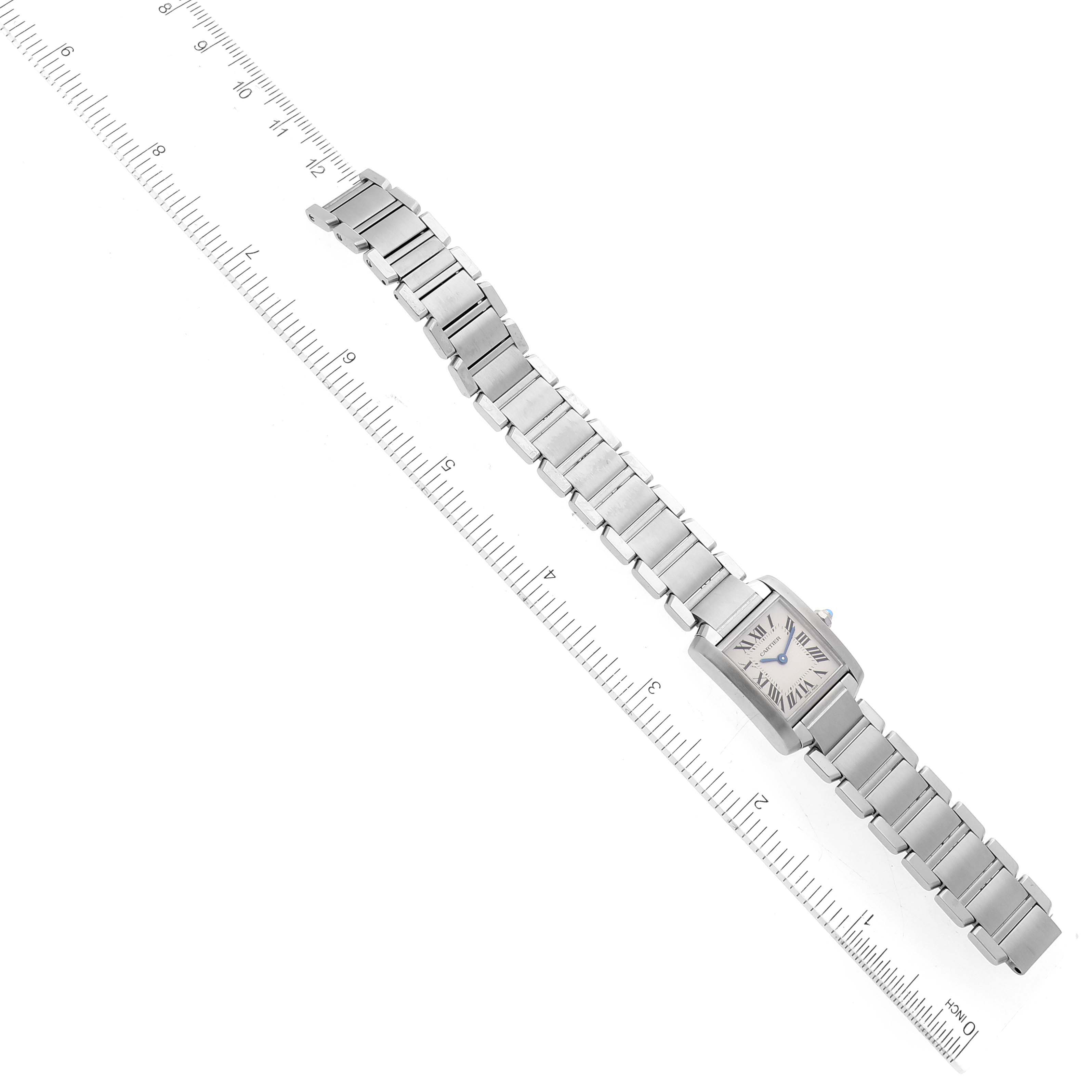 The image shows a top view of a Cartier Tank Francaise W51008Q3 Women
s Stainless Steel Silver Dial W51008Q3 Women
s Stainless Steel Silver Dial watch, displaying its bracelet and square face, placed alongside a ruler.