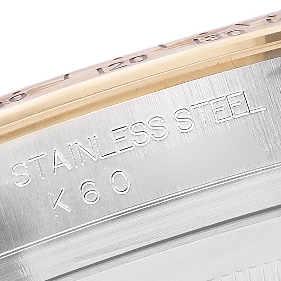 This close-up shows the stainless steel case side, engraved with text, of a Rolex Daytona 116523 Men
s Steel and Gold (two tone) White Dial 116523 Men
s Steel and Gold (two tone) White Dial model watch.