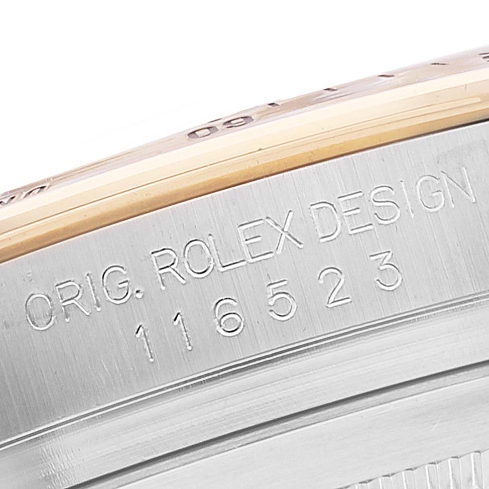 The image shows a close-up of the engraved side profile of a Rolex Daytona 116523 Men
s Steel and Gold (two tone) White Dial 116523 Men
s Steel and Gold (two tone) White Dial watch, including the model number 116523.