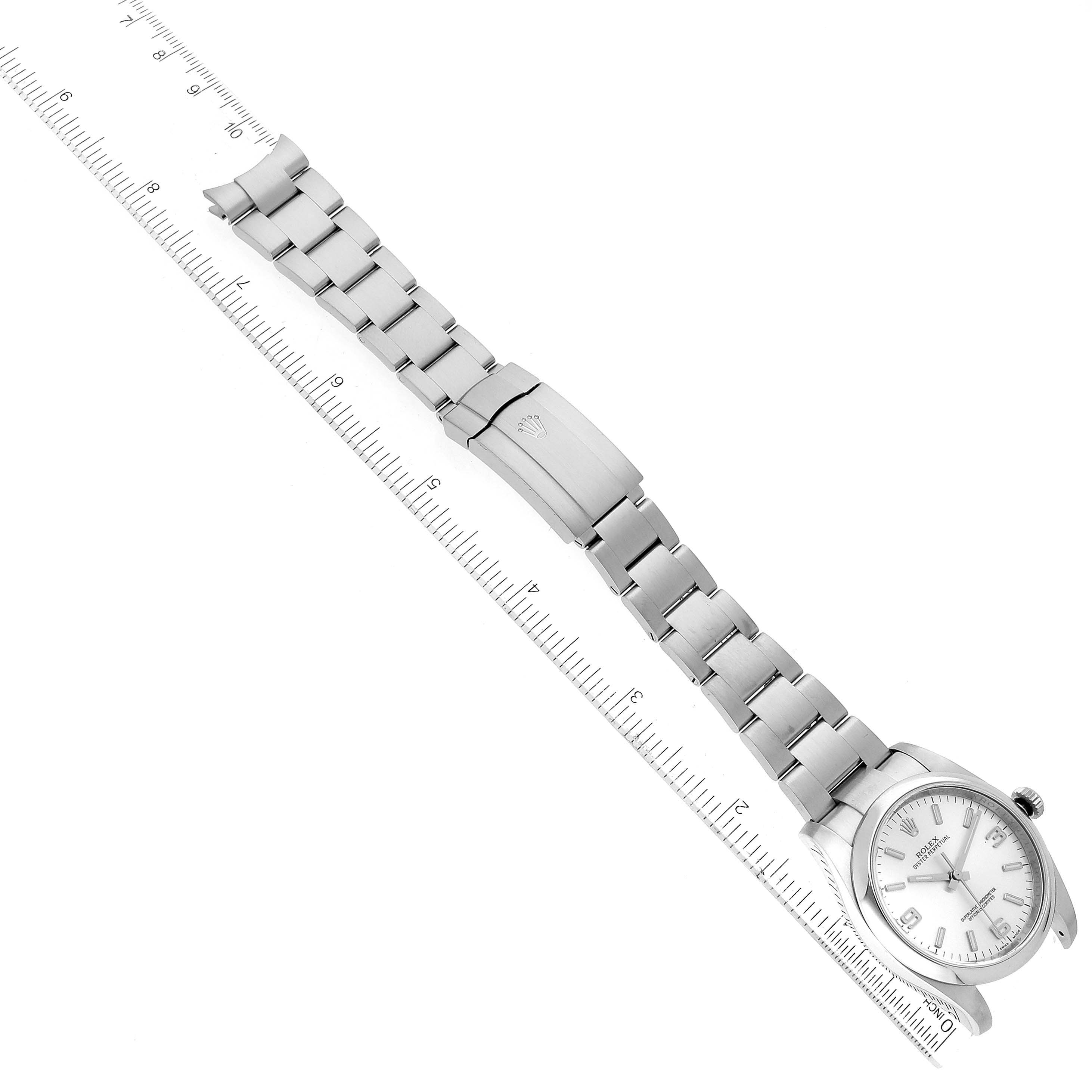 The image shows a Rolex Oyster Perpetual 116000 Men's Stainless Steel Silver Dial 116000 Men's Stainless Steel Silver Dial watch laid flat with its face and metal bracelet fully visible alongside a ruler.