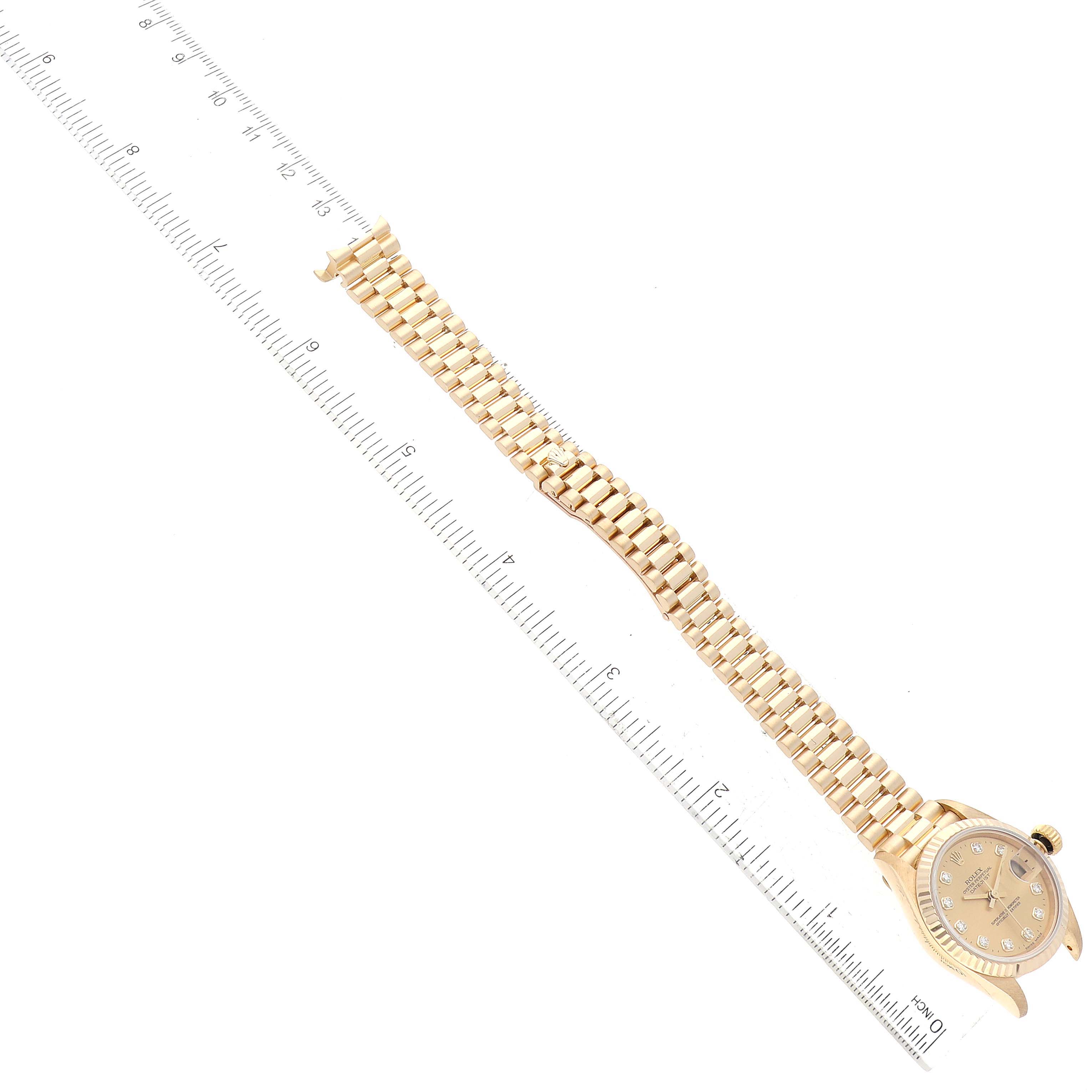 This image shows a Rolex Datejust 69178 Women's Yellow Gold Champagne Dial 69178 Women's Yellow Gold Champagne Dial watch laid flat with its gold bracelet stretched out beside a ruler.
