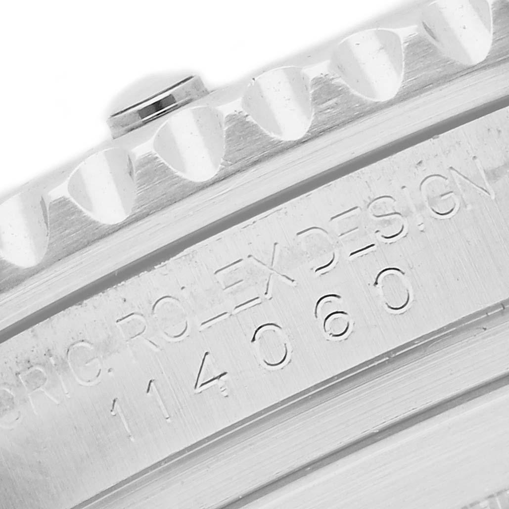 The image shows a close-up of the Rolex Submariner's bezel and engraved model number 114060, highlighting its textured edge and design inscription.