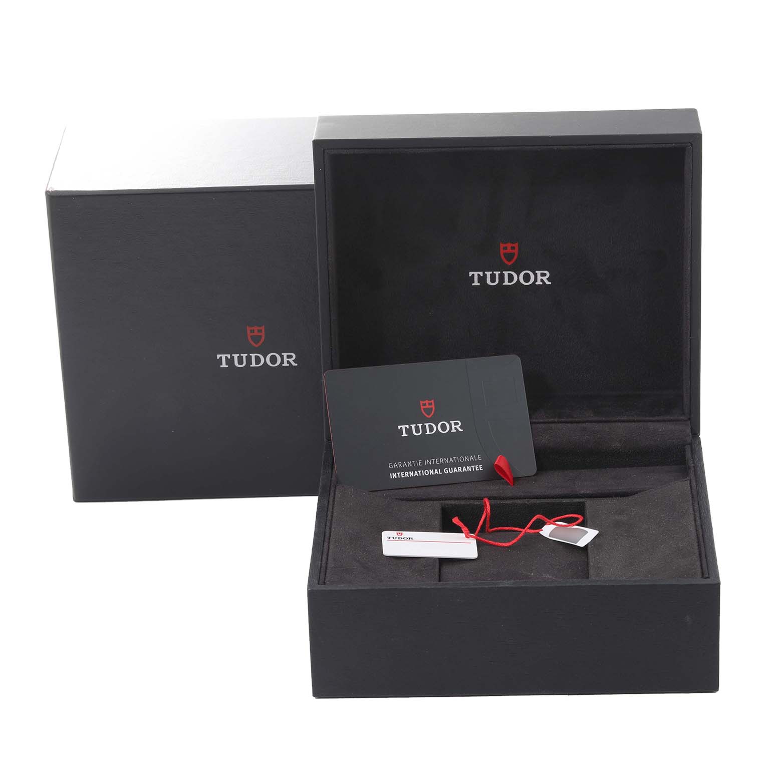 The image shows the open packaging and accessories of the Tudor Heritage Black Bay, including the guarantee card and tag.