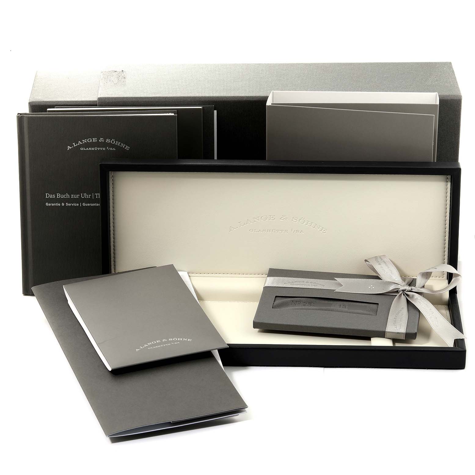 The image shows the packaging and accessories for the 1815 model by A. Lange 
Söhne, including the watch box, manuals, and paperwork.