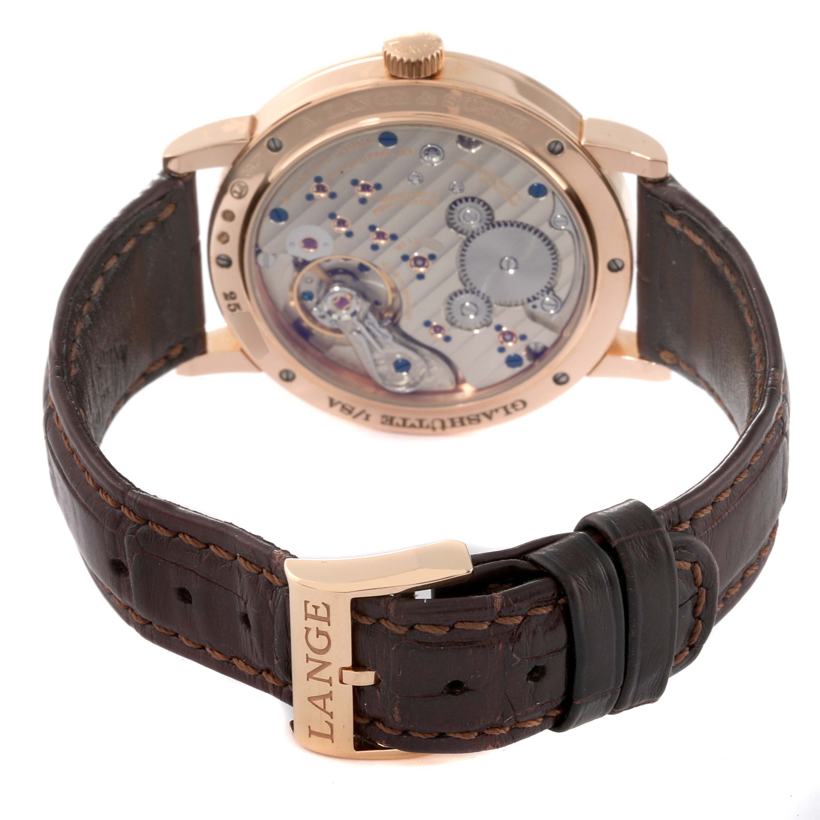 The image shows the back view of an A. Lange 
Sohne 1815 234.032 Men
s Rose Gold Silver Dial watch, highlighting its movement and leather strap.