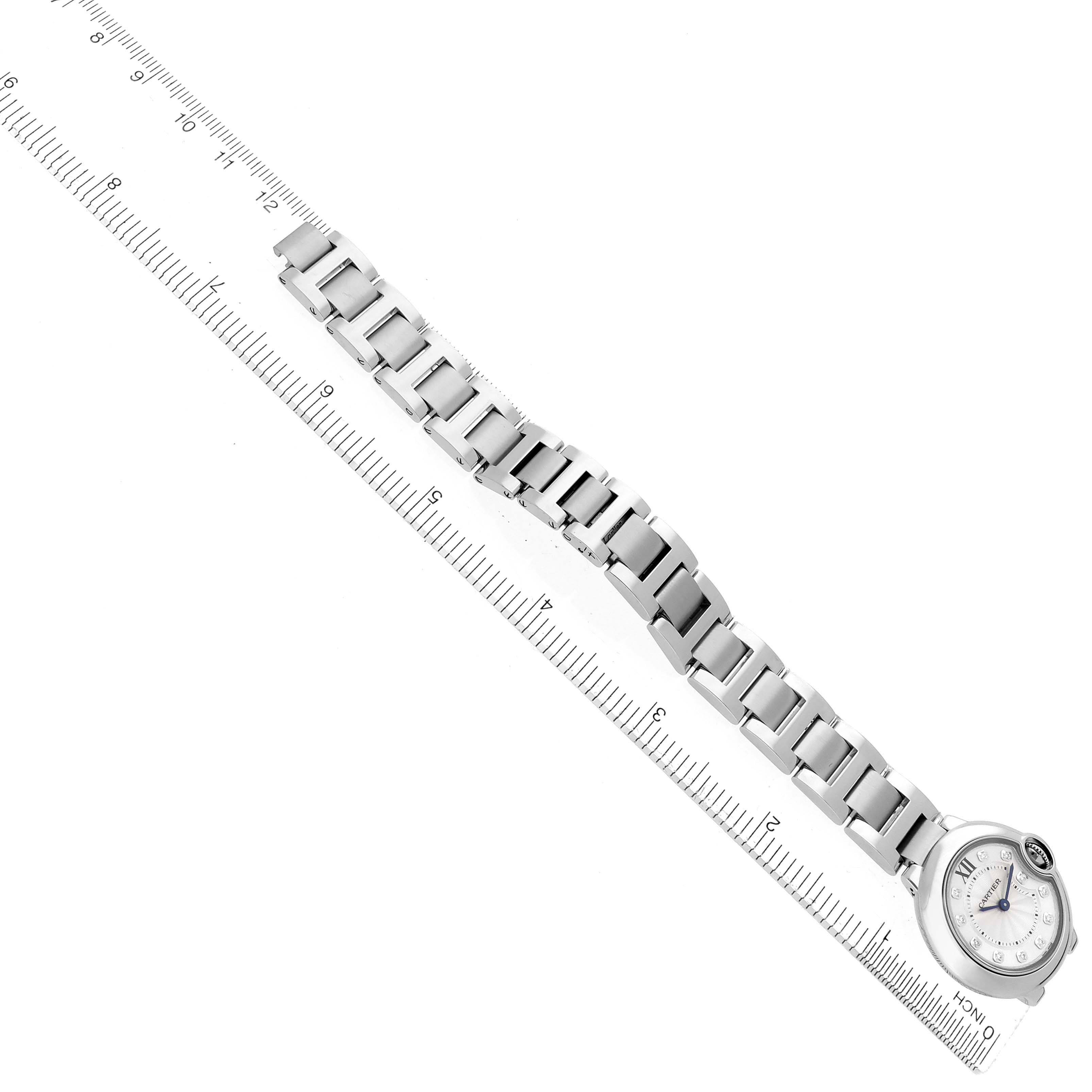 The Cartier Ballon Bleu WE902073 Women
s Stainless Steel Silver Dial watch is shown from a top view, displaying the entire bracelet and the face next to a ruler.