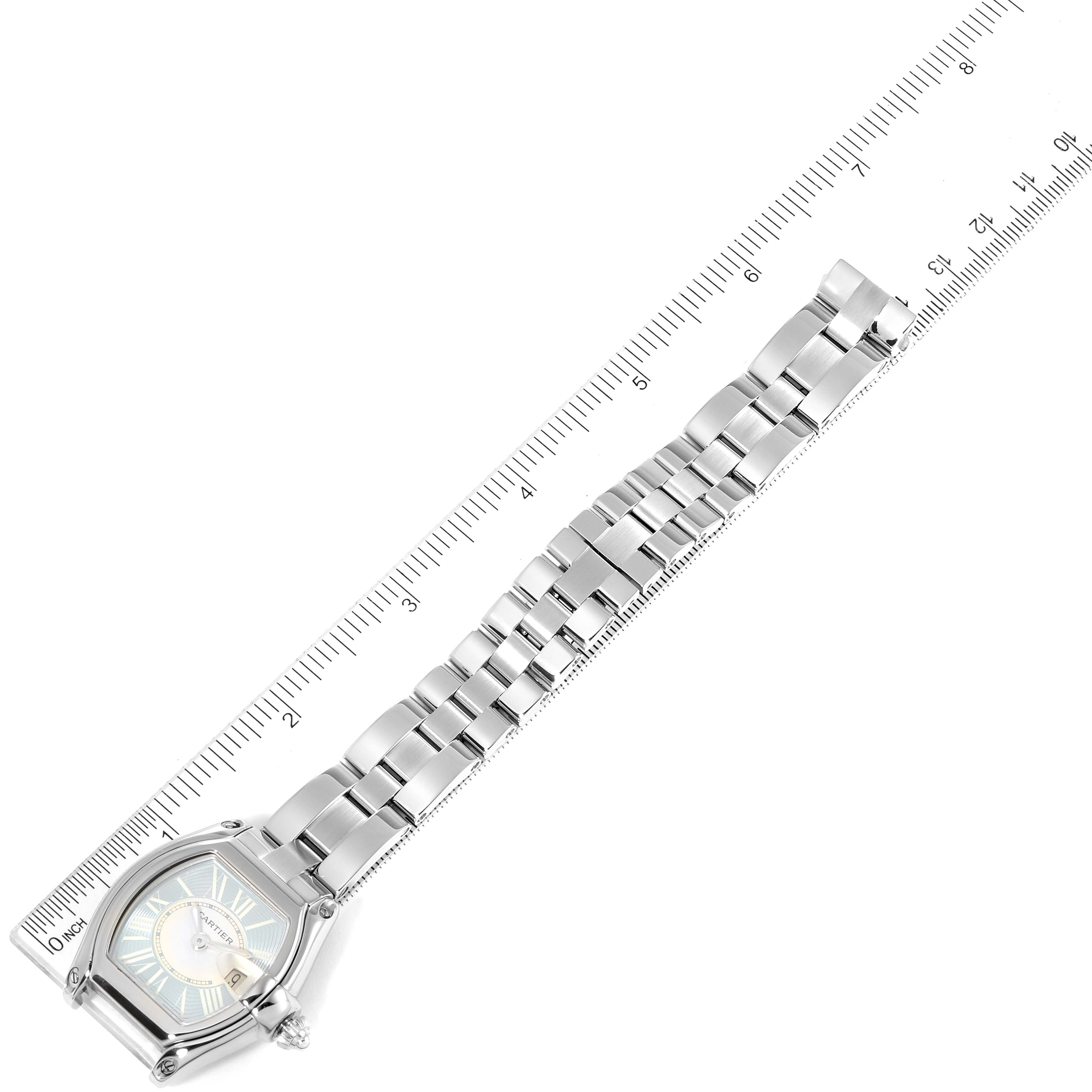 The image shows a Cartier Roadster W62053V3 Women's Stainless Steel Blue Dial W62053V3 Women's Stainless Steel Blue Dial watch partially extended alongside a measuring ruler, highlighting its band and face.