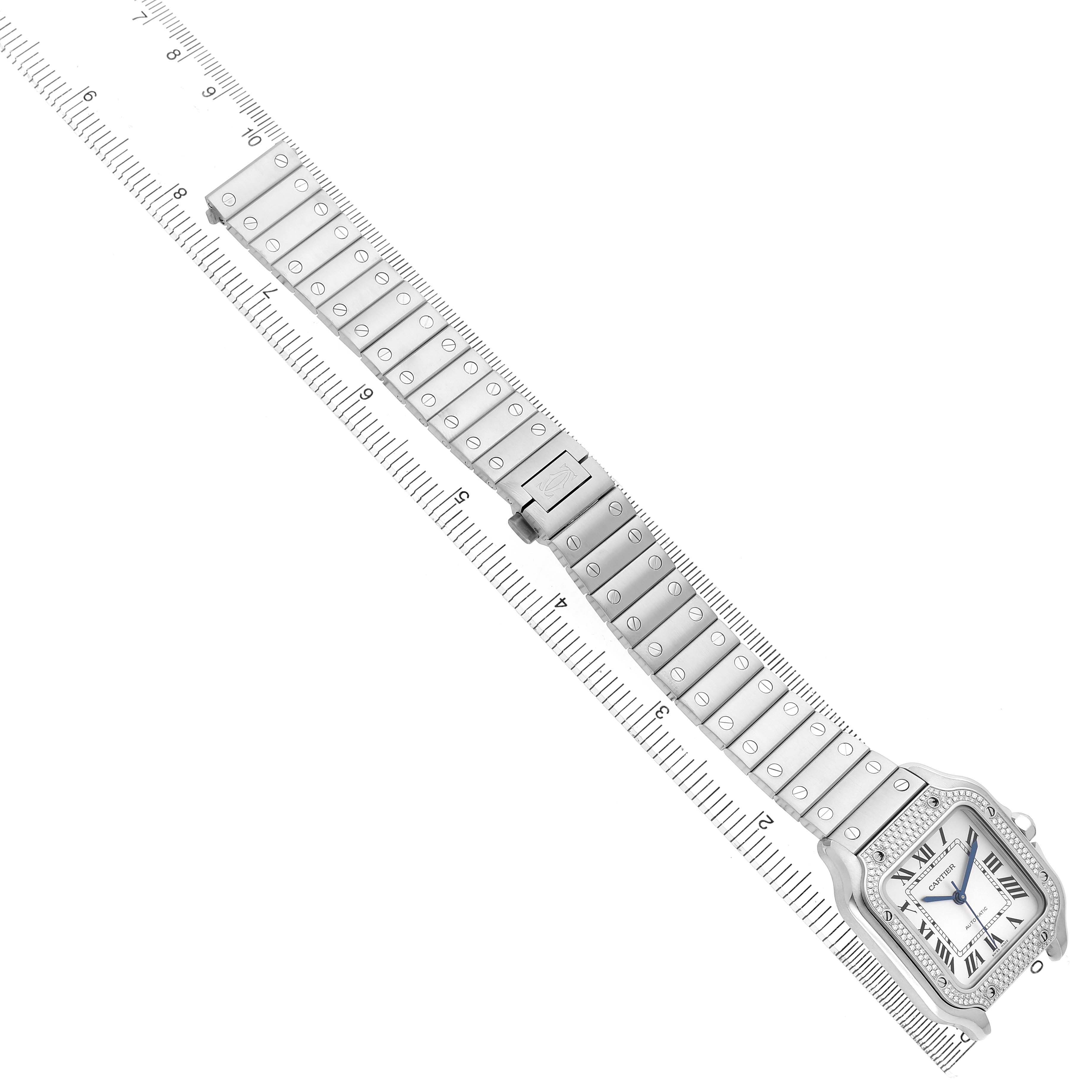 The Cartier Santos W4SA0005 Men's Stainless Steel Silver Dial watch is shown at an angle displaying the face, bracelet, and a ruler for scale.