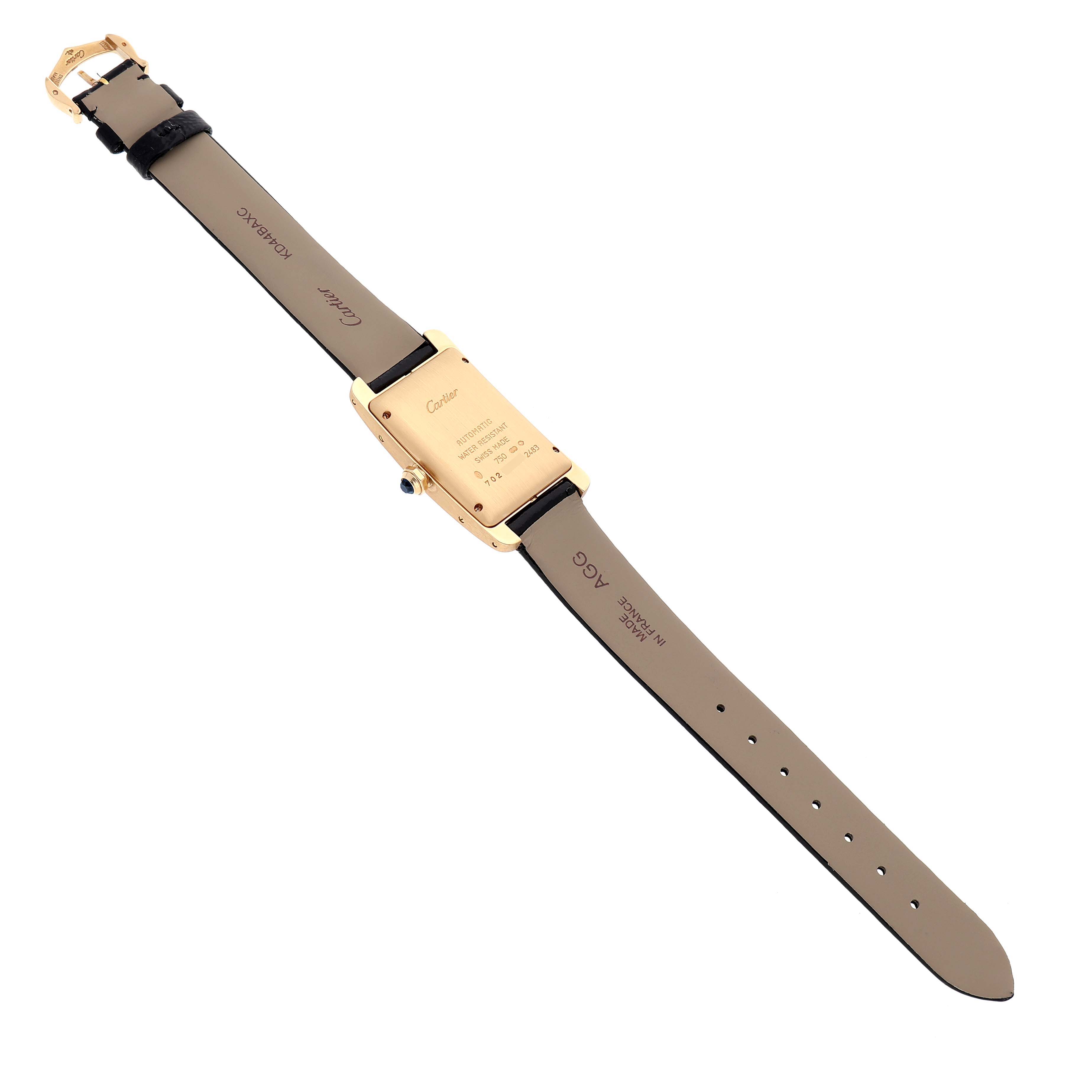 The Cartier Tank Americaine W2603556 Men's Yellow Gold Silver Dial watch is shown from the back, displaying its case back, straps, and buckle.