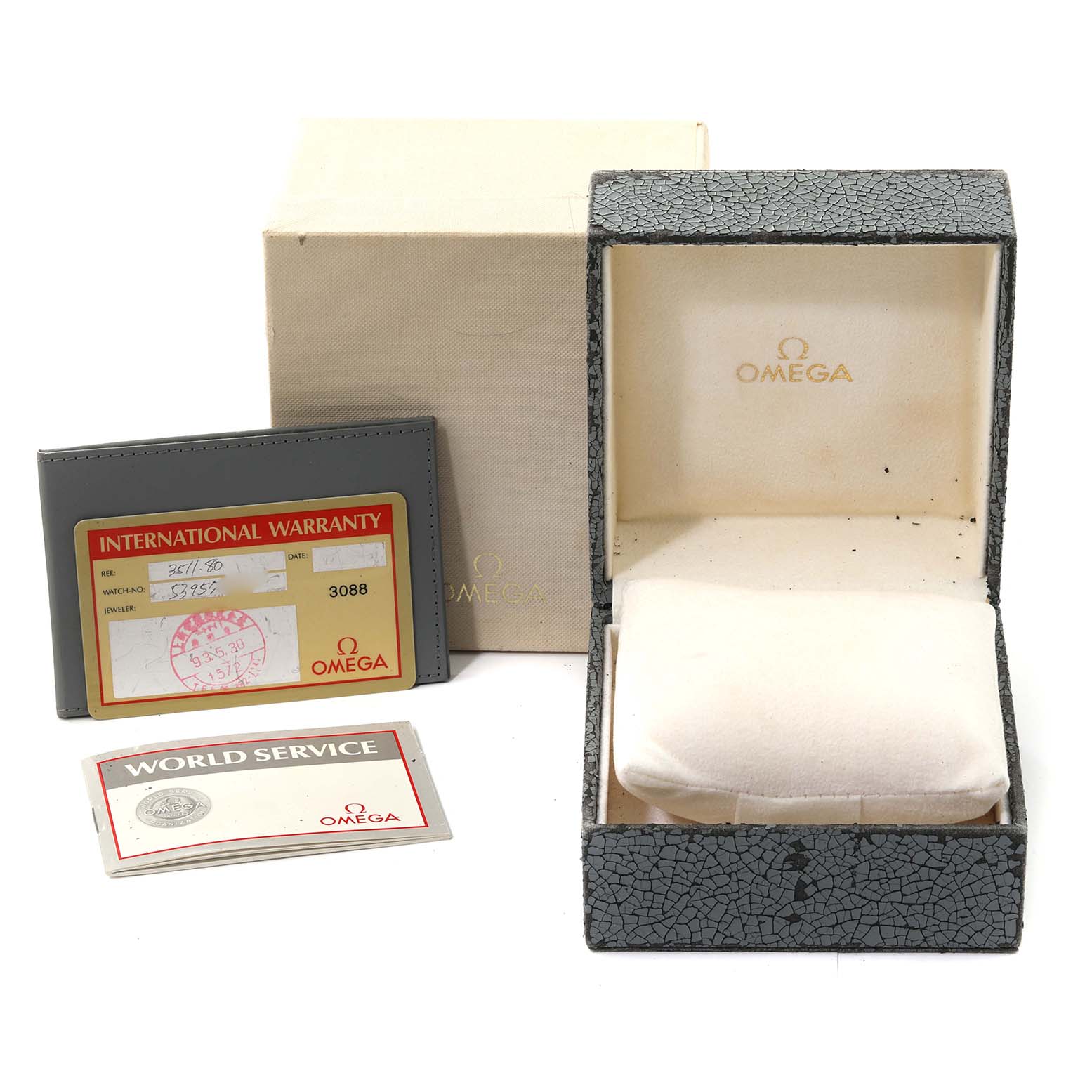 The image shows an Omega Speedmaster 3511.80.00 Men
s Stainless Steel Blue Dial 3511.80.00 Men
s Stainless Steel Blue Dial watch box, warranty card, and service booklet at an angle revealing all contents.