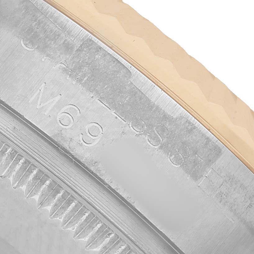 The image shows a close-up of the Mid-Size Rolex watch's bezel and case edge, highlighting engraved lettering and serrated edges.