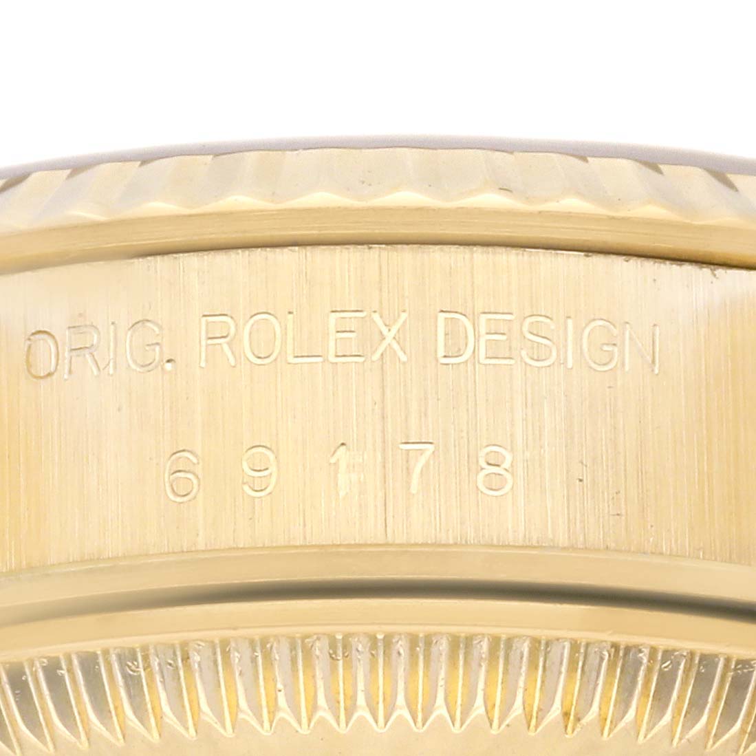 The image shows a close-up of the Rolex President 69178 Women's Yellow Gold Champagne Dial 69178 Women's Yellow Gold Champagne Dial model's fluted bezel with "ORIG. ROLEX DESIGN 69178" engraved.