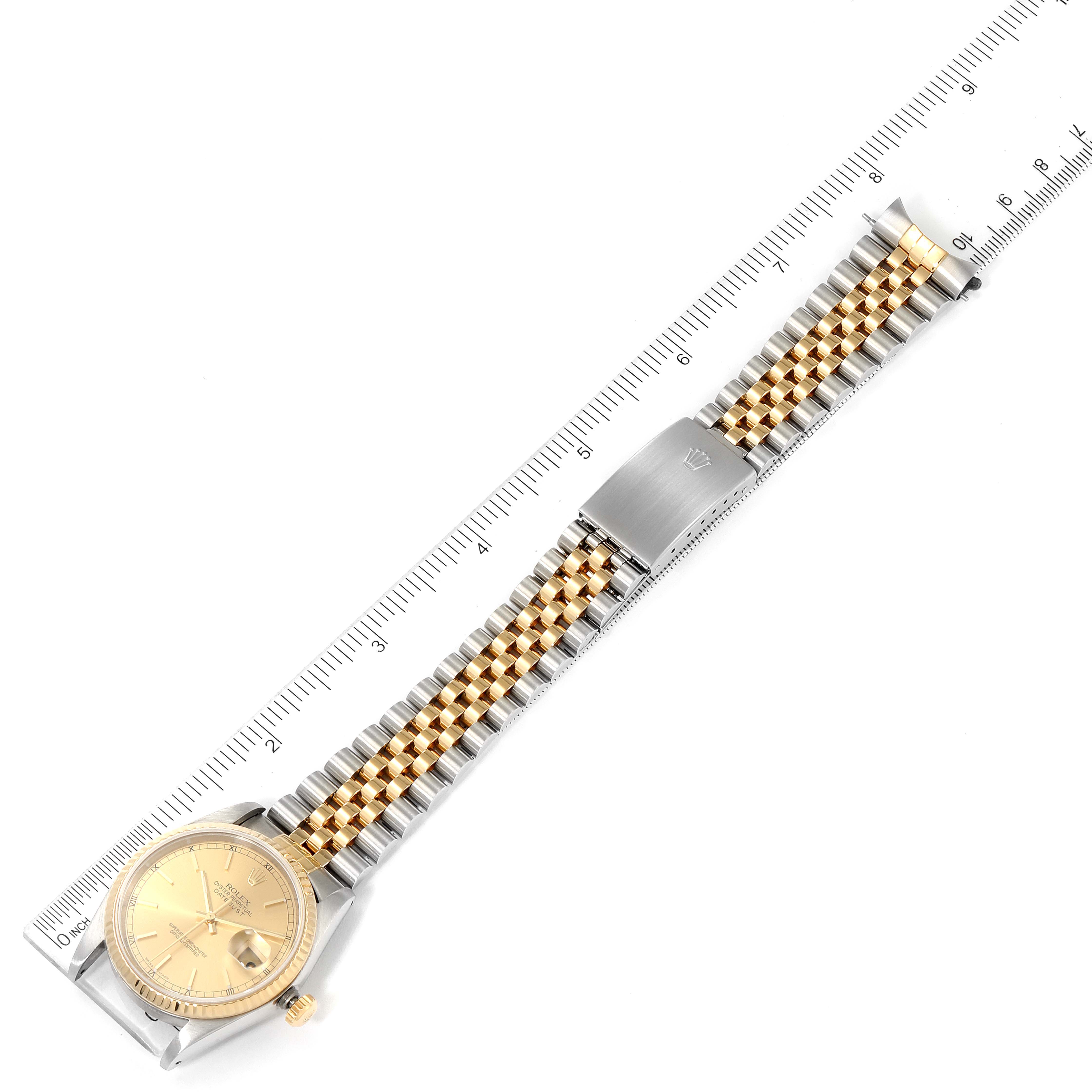 The Rolex Datejust 16233 Men's Steel and Gold (two tone) Champagne Dial 16233 Men's Steel and Gold (two tone) Champagne Dial watch is shown from a top-down angle, displaying the face, bracelet, and clasp alongside a ruler.