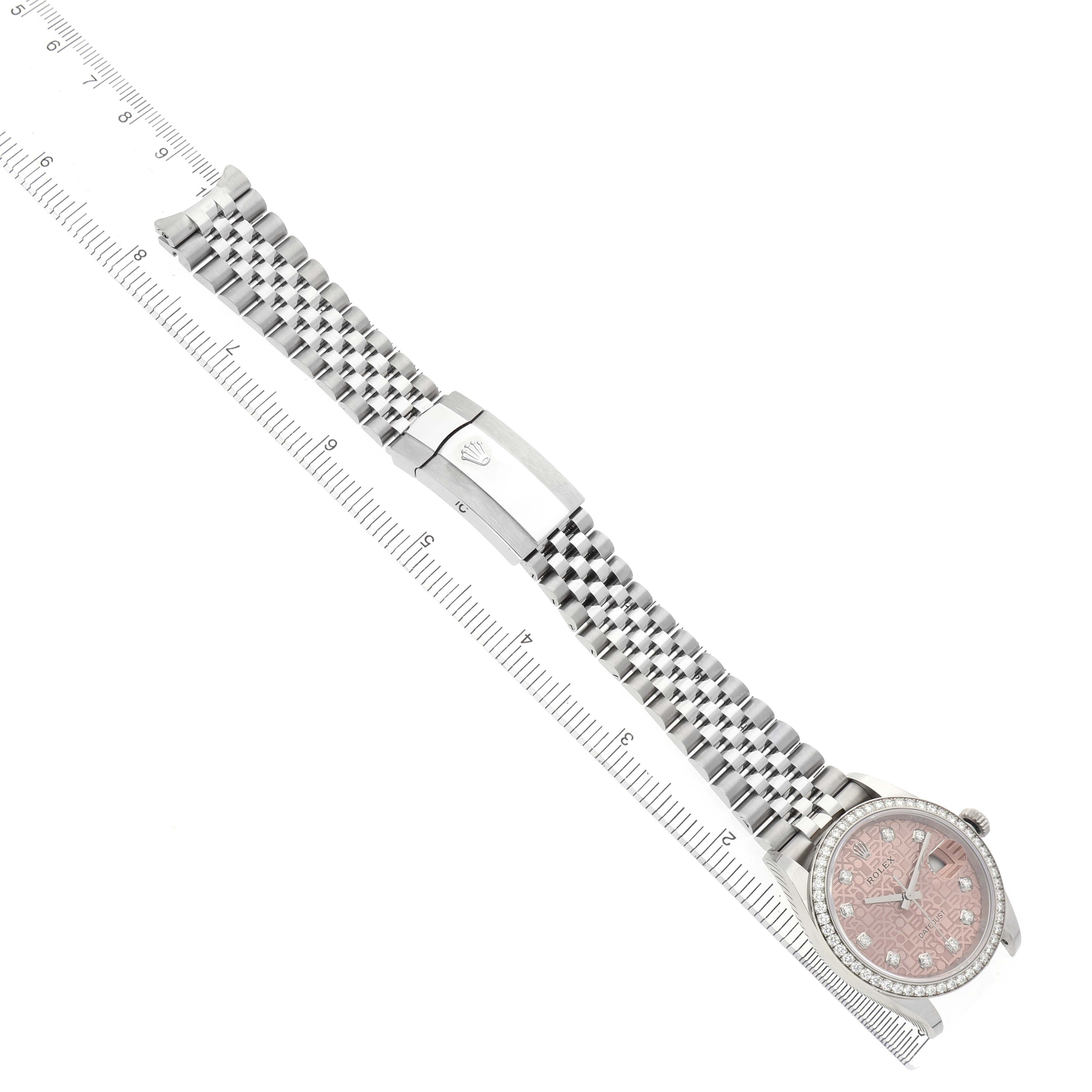 The Rolex Datejust 126284 Men's Stainless Steel Pink Dial watch is shown at a diagonal angle, displaying the bracelet, clasp, dial, and bezel with a ruler for scale.