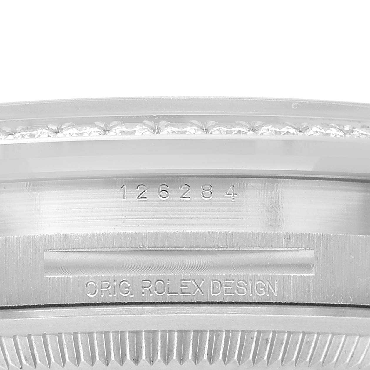 The image shows a close-up of the side of a Rolex Datejust 126284 Men's Stainless Steel Pink Dial watch, featuring engraved text and the fluted bezel.