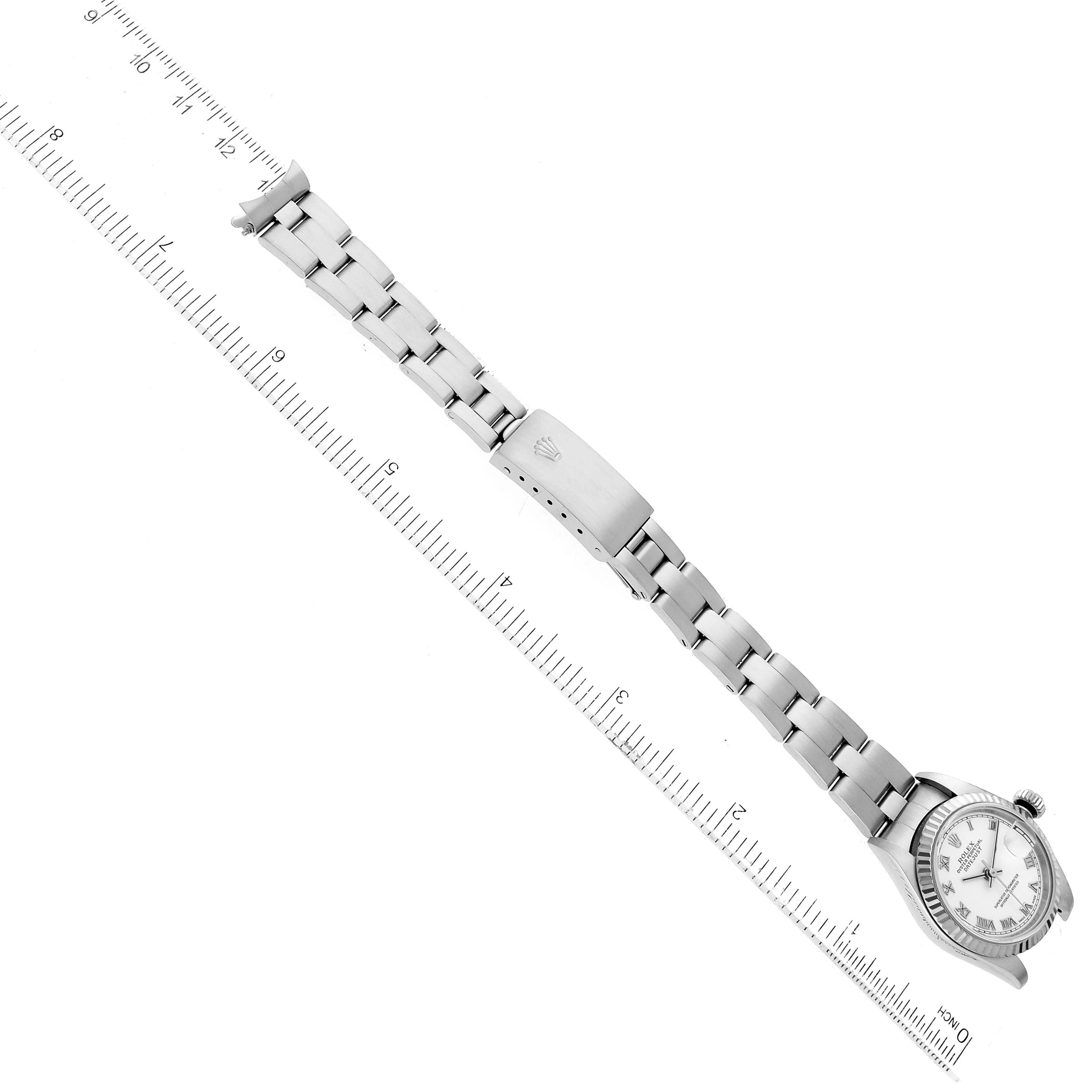 The image shows the Rolex Datejust 79174 Women's Stainless Steel White Dial 79174 Women's Stainless Steel White Dial watch laid flat against a ruler, displaying the watch face, bracelet, and clasp.