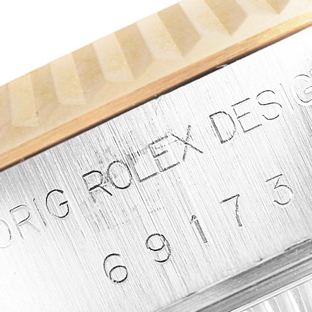The image shows a close-up view of the engraved case side and the fluted bezel of a Rolex Datejust 69173 Women
s Steel and Gold (two tone) Beige Dial 69173 Women
s Steel and Gold (two tone) Beige Dial model.