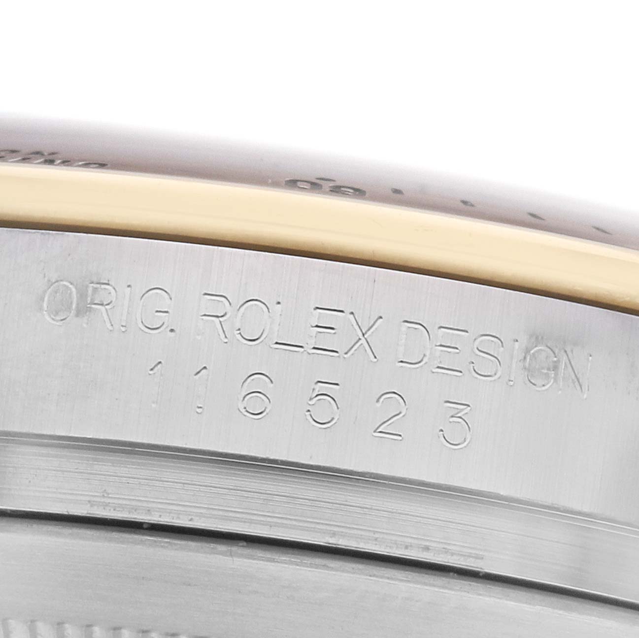 The image shows the side of a Rolex Daytona 116523 Men
s Steel and Gold (two tone) Black Dial, highlighting the engraved model number and design inscription on the case.