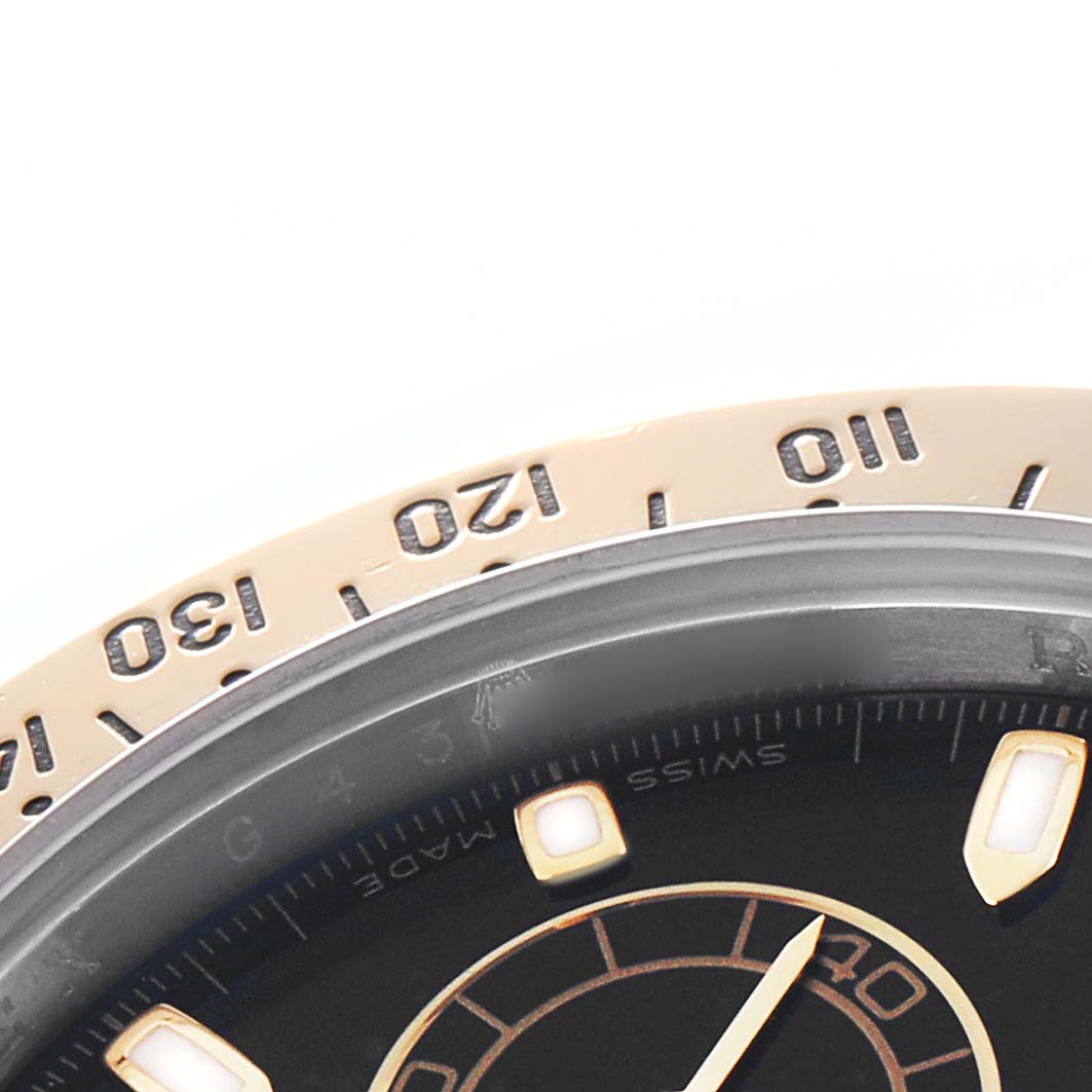 The image shows a partial close-up of the bezel and dial of a Rolex Daytona 116523 Men
s Steel and Gold (two tone) Black Dial watch.