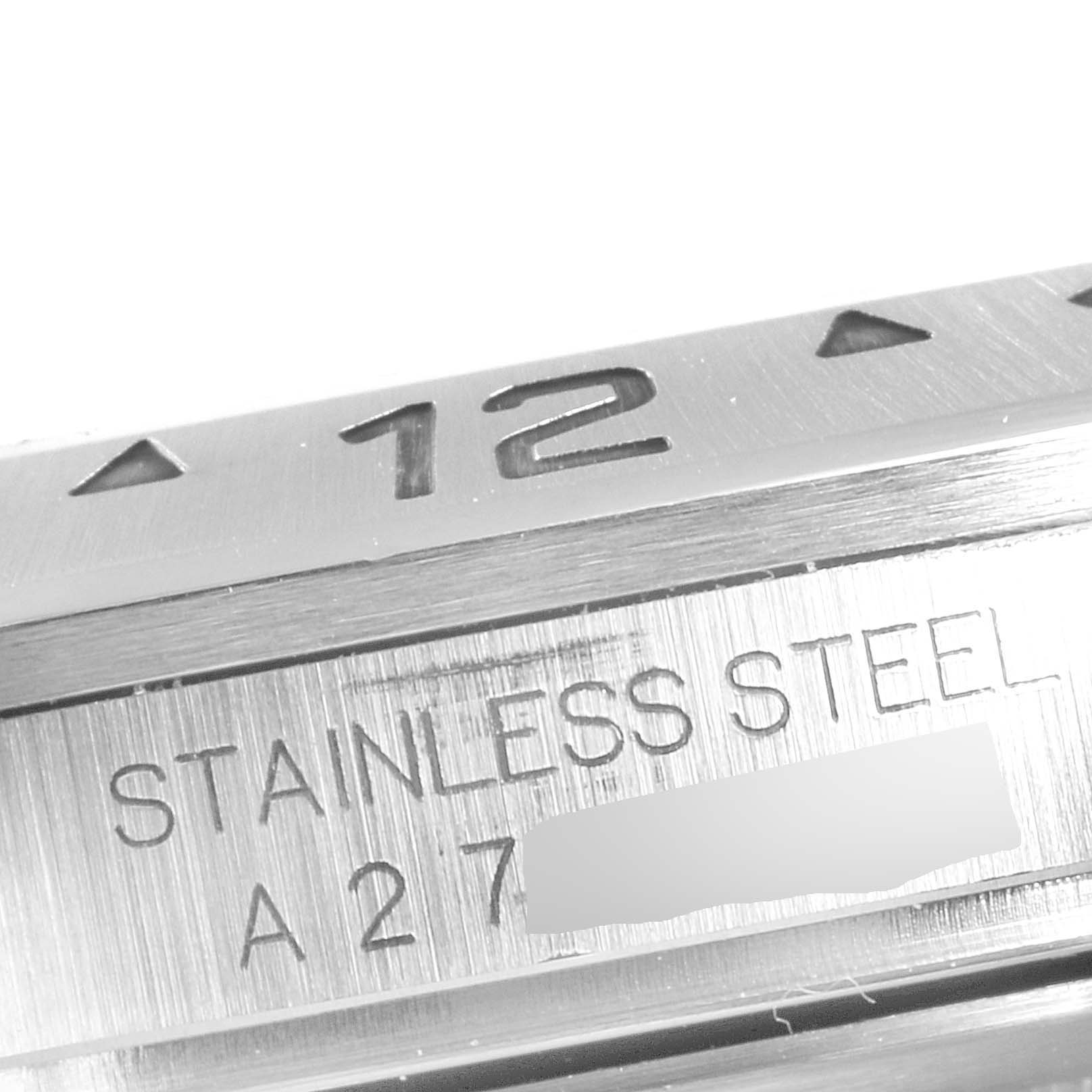 The image shows a close-up of the bezel and case side of a Rolex Explorer 16570 Men
s Stainless Steel Black Dial 16570 Men
s Stainless Steel Black Dial watch, focusing on the "12" marker and "STAINLESS STEEL" engraving.