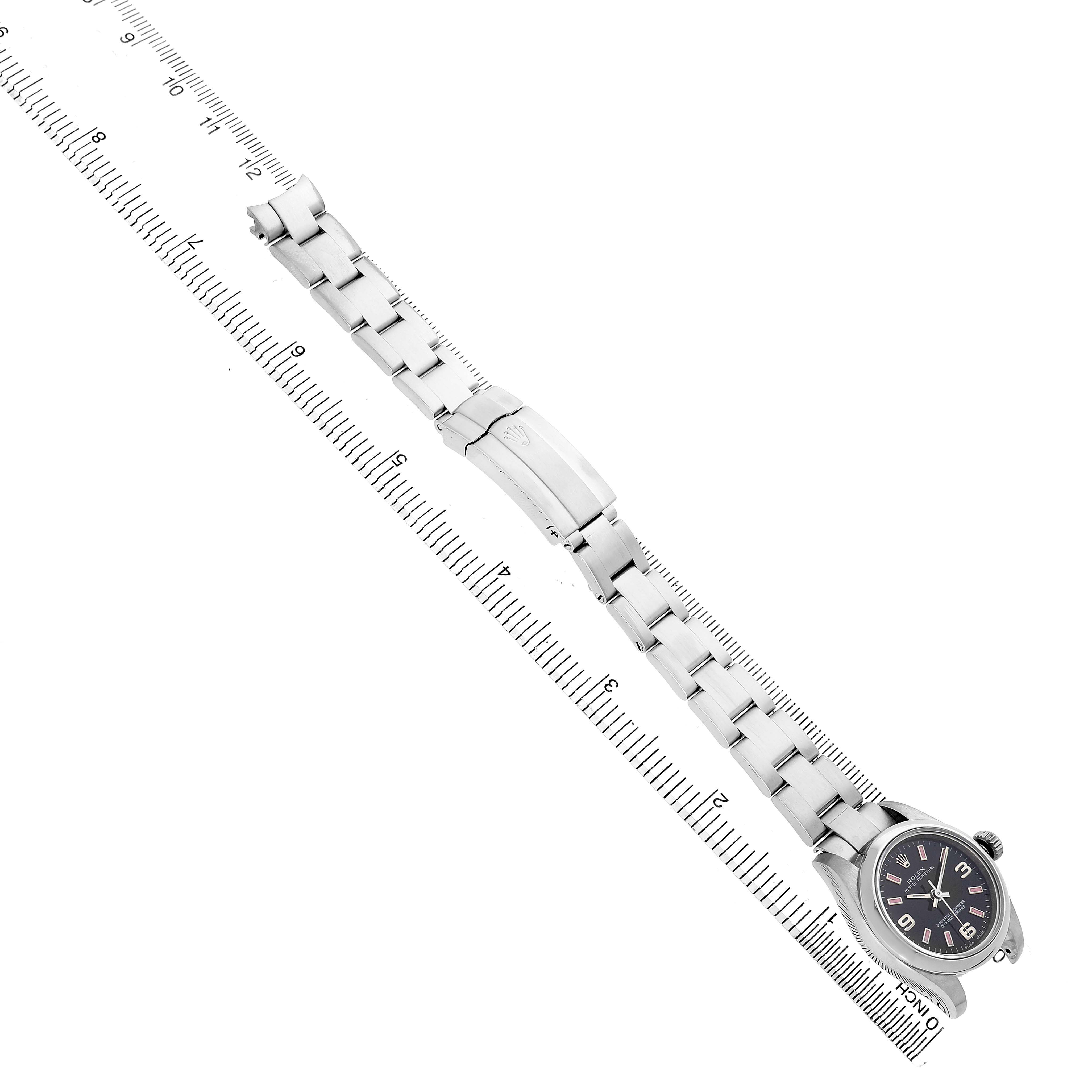The image shows a Rolex Oyster Perpetual 176200 Womens Stainless Steel Black Dial watch from the side, featuring the bracelet and clasp, alongside a ruler.