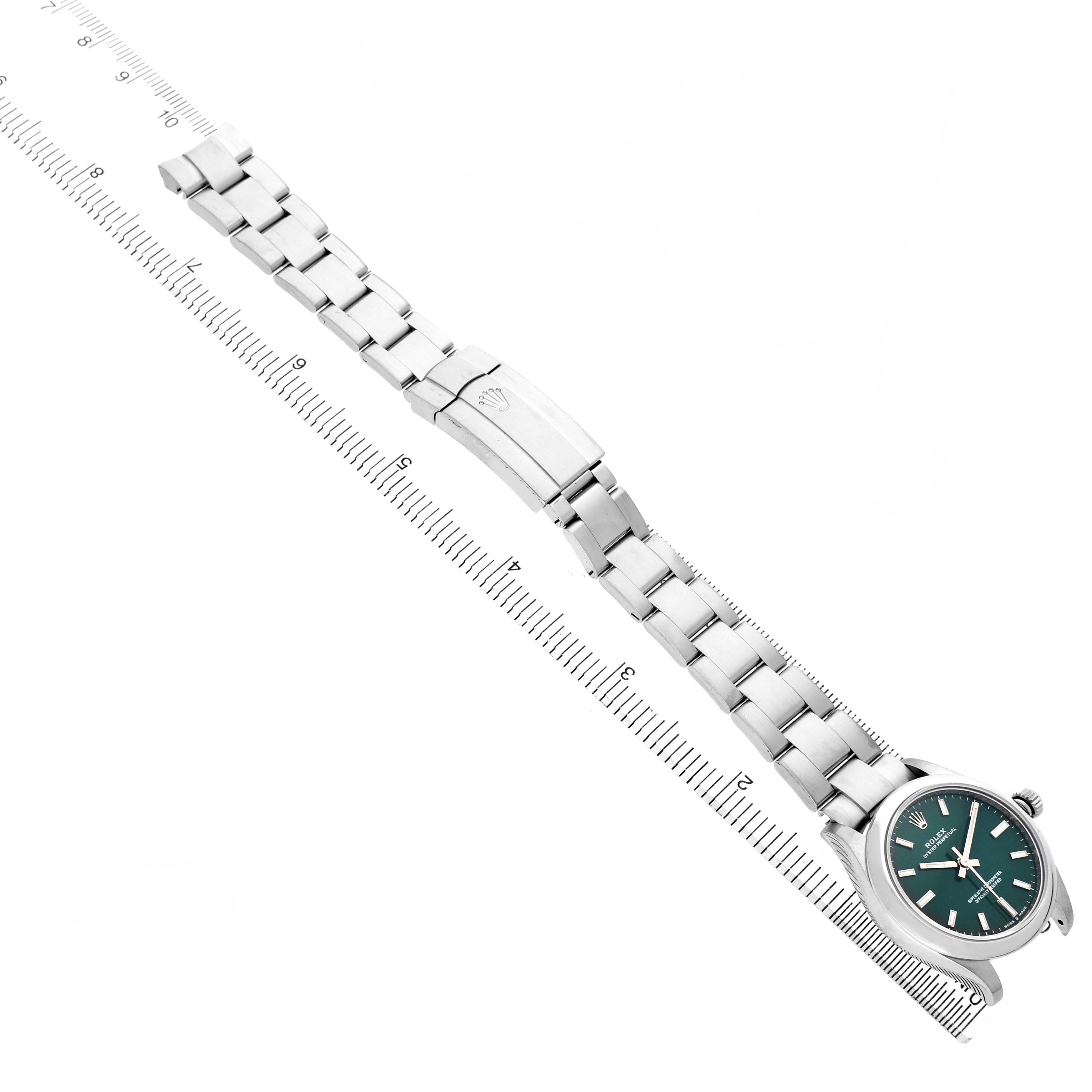 The Rolex Mid-Size 277200 Women's Stainless Steel Green Dial watch is shown at an angle highlighting its full bracelet and clasp, alongside a ruler for scale.