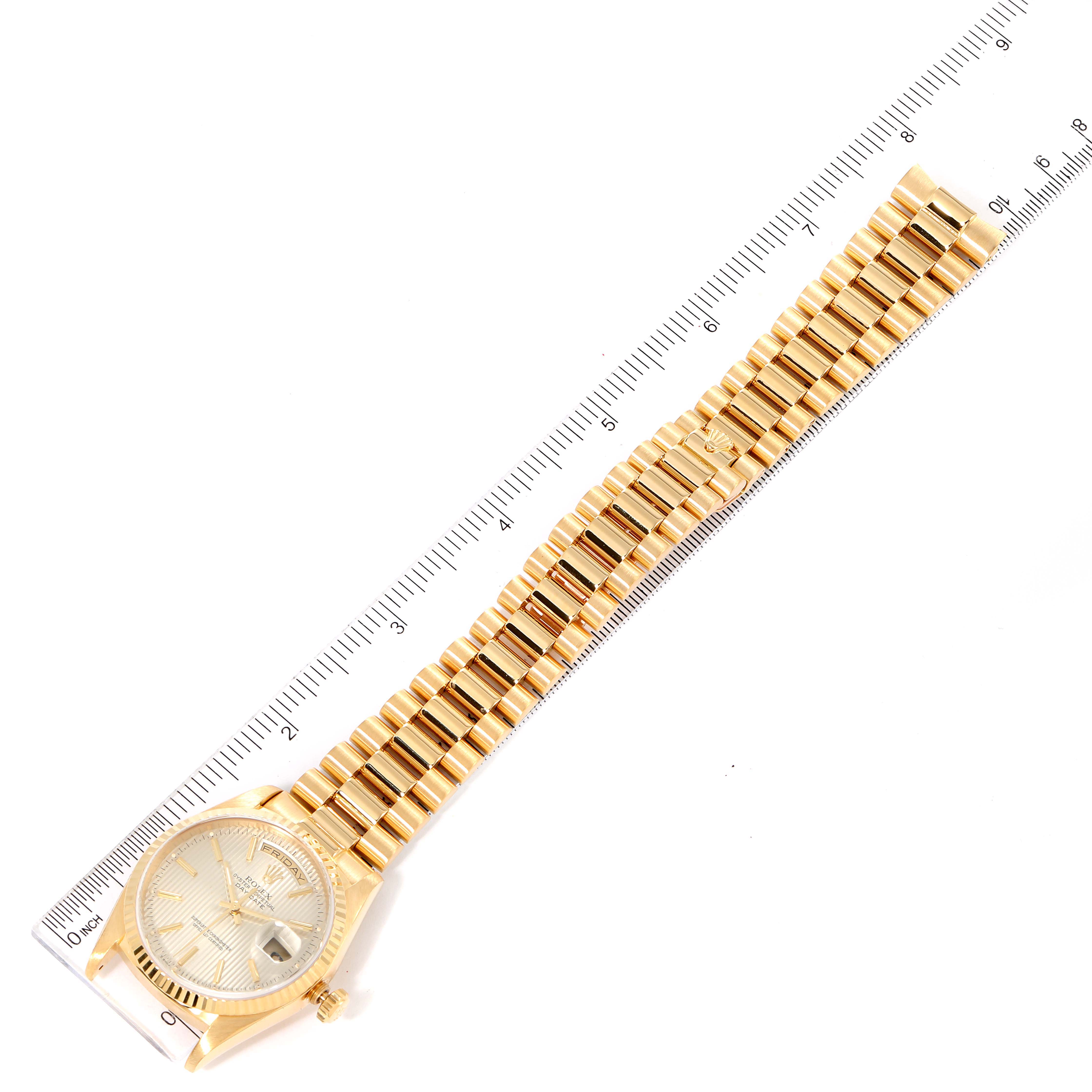 This image shows a Rolex President 18238 Men's Yellow Gold Silver Dial 18238 Men's Yellow Gold Silver Dial model watch laid flat next to a ruler, displaying the watch face and gold bracelet.