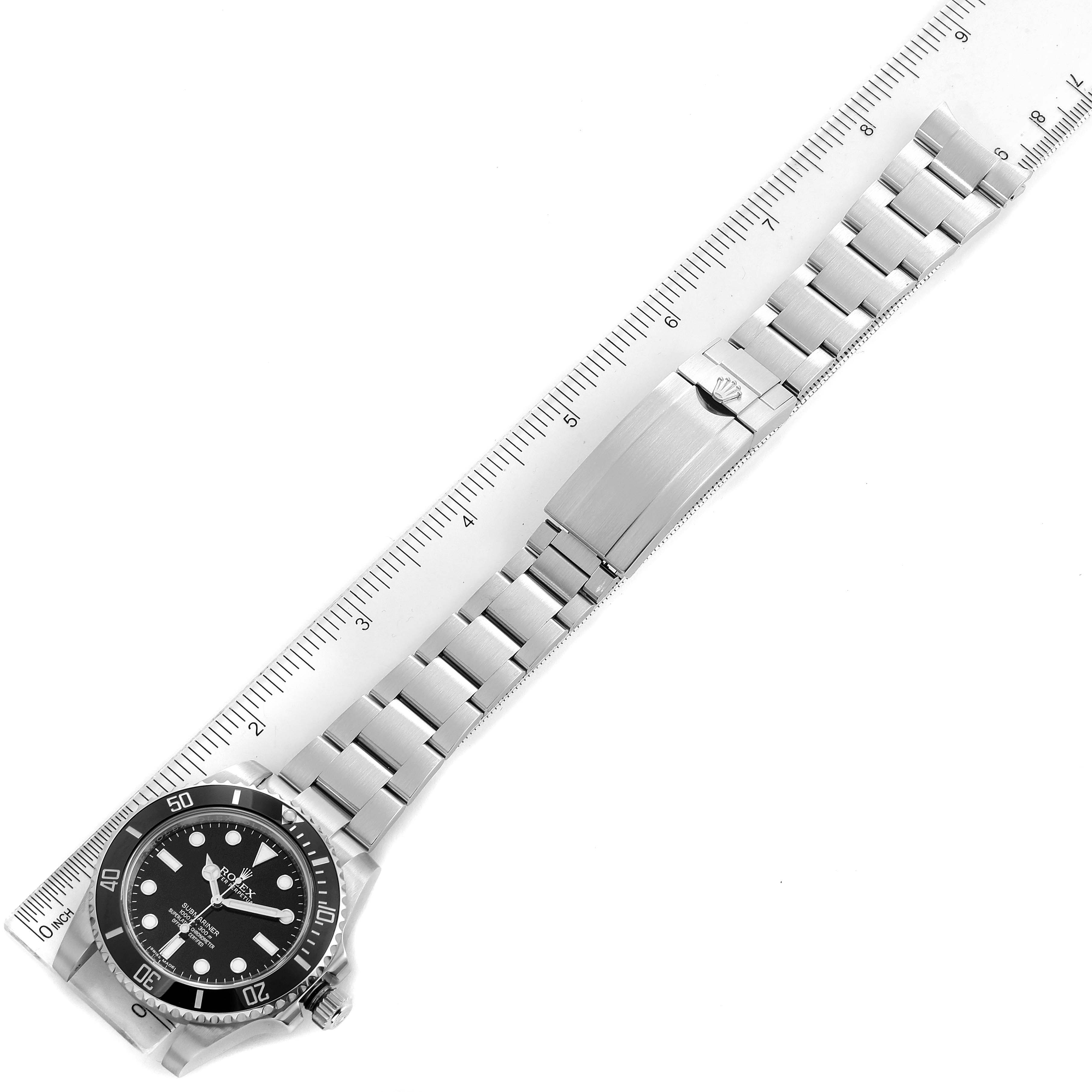 The image shows a top-down view of a Rolex Submariner 114060 Men
s Stainless Steel Black Dial 114060 Men
s Stainless Steel Black Dial watch with a metal bracelet placed alongside a ruler.