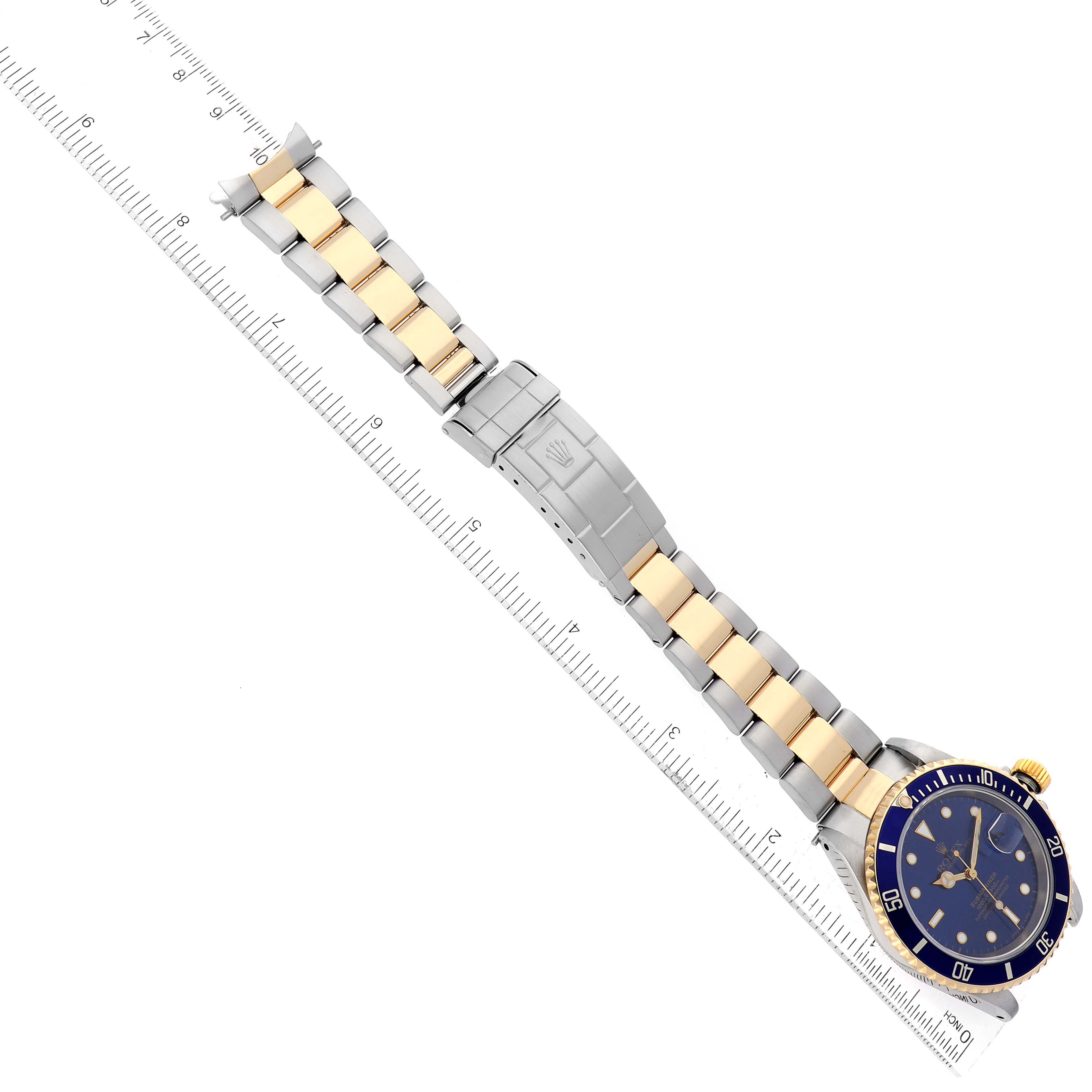This image shows a Rolex Submariner 16613 Men's Steel and Gold (two tone) Blue Dial 16613 Men's Steel and Gold (two tone) Blue Dial watch measured alongside a ruler, displaying the band, clasp, and face.