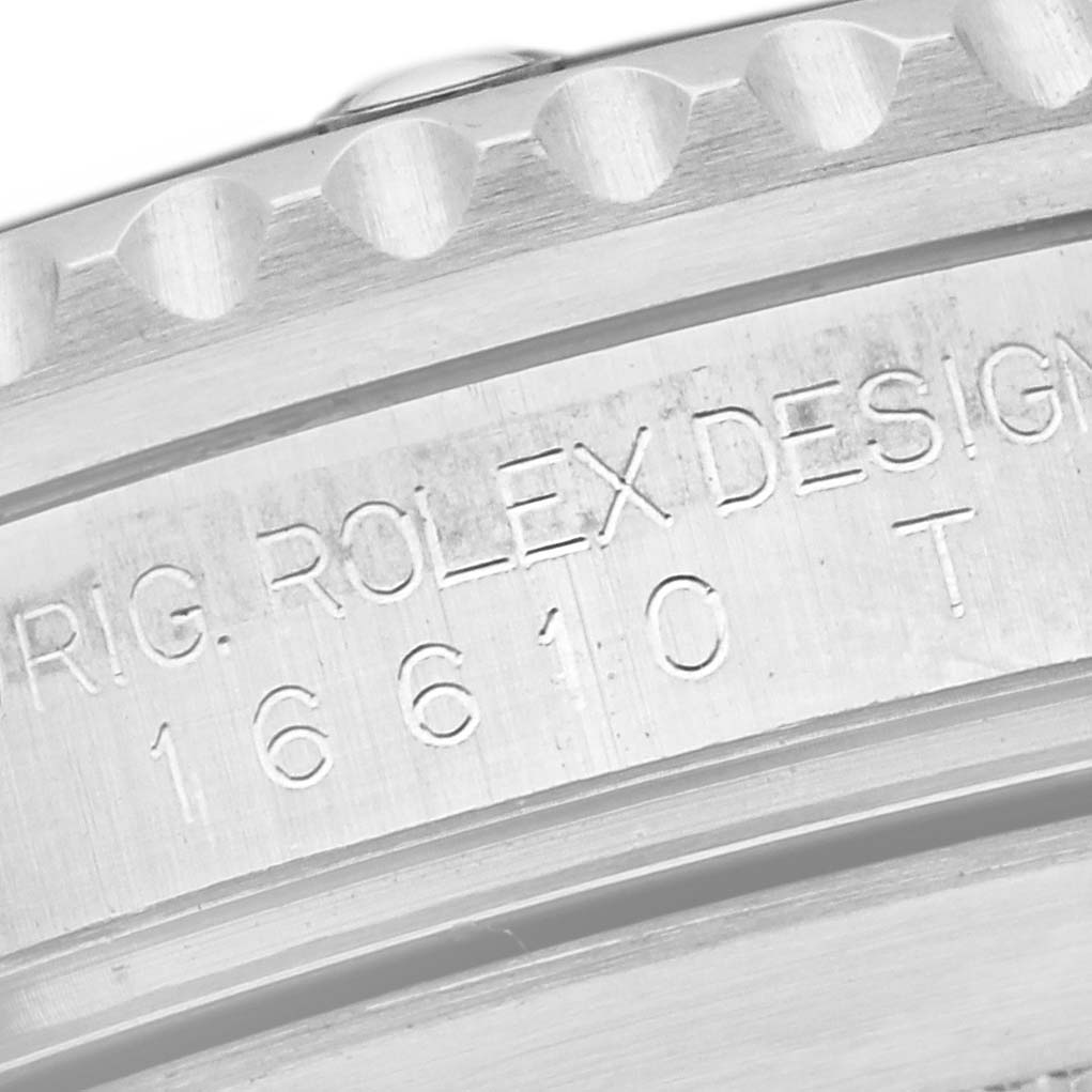 The image shows an angled close-up of the edge of a Rolex Submariner 16610 Men
s Stainless Steel Black Dial 16610 Men
s Stainless Steel Black Dial, highlighting its engraved serial number on the case.