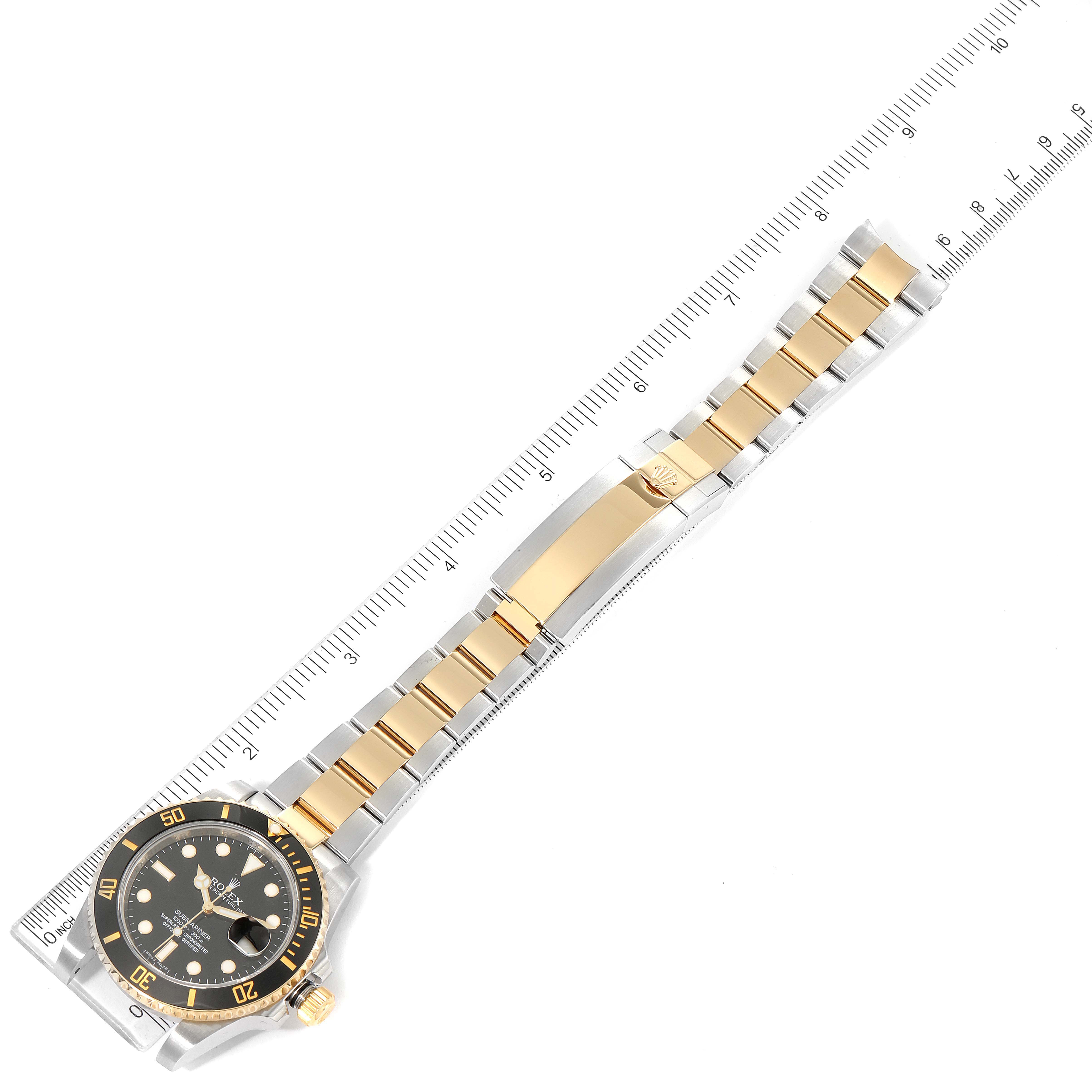 The image shows a top view of the Rolex Submariner 116613 Men
s Steel and Gold (two tone) Black Dial 116613 Men
s Steel and Gold (two tone) Black Dial
s full watch with a ruler for size reference.