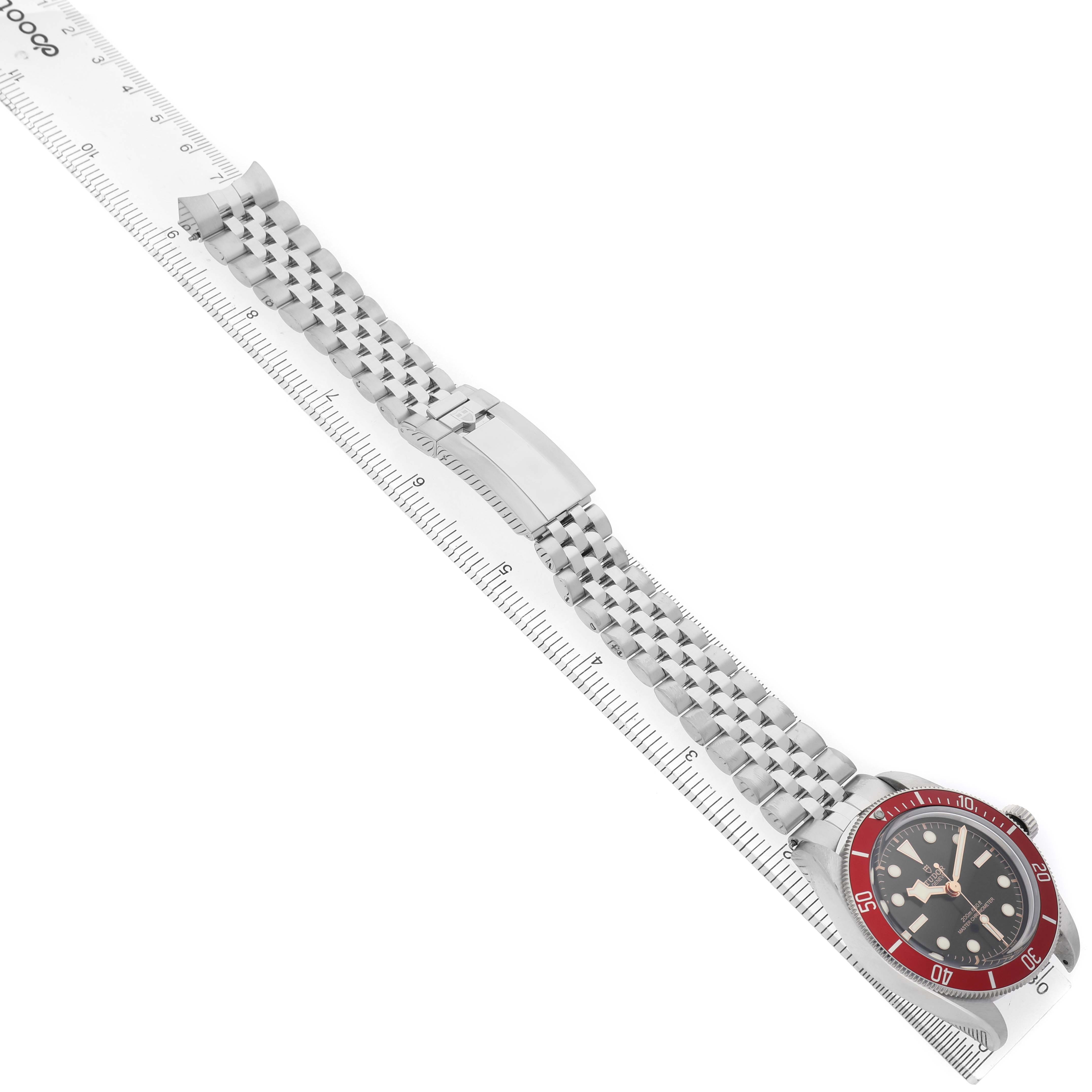 The Tudor Heritage Black Bay 7941A1A0 Men's Stainless Steel Black Dial watch is shown at an angled view, with its dial, bezel, and bracelet fully visible alongside a ruler.