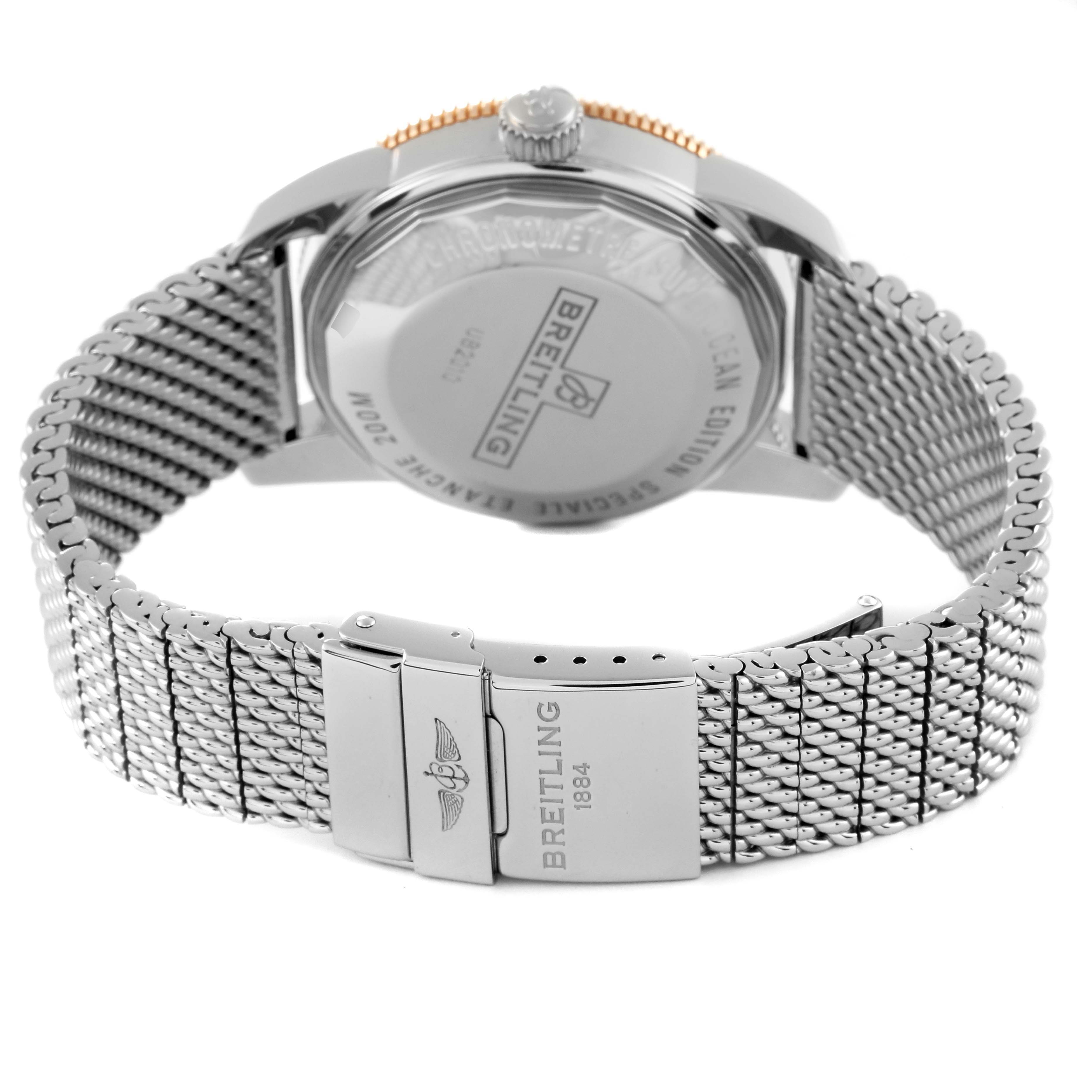 The image shows the back of a Breitling Superocean UB2010 Men's Steel and Gold (two tone) Black Dial UB2010 Men's Steel and Gold (two tone) Black Dial watch, highlighting its case back, crown, and mesh bracelet with clasp.